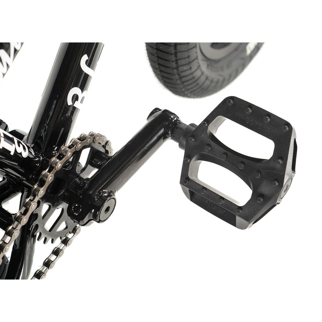 Close-up of the black crank, chainring, chain, and a rectangular plastic pedal next to the tire on the Division Blitzer 12 Inch Bike.