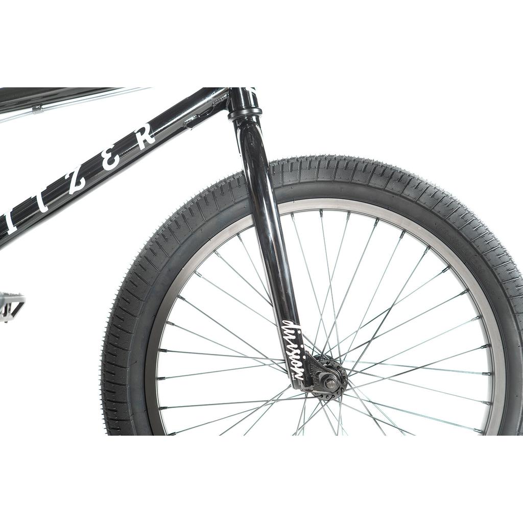 Close-up of the front wheel and fork of a black Division Blitzer 20 Inch Bike, with white lettering on the frame and fork.