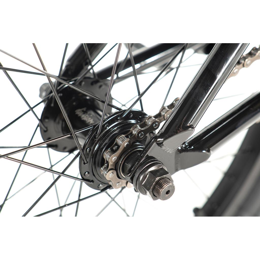 Close-up of the Division Blitzer 20 Inch Bike’s rear wheel hub, highlighting the chain, sprocket, spokes, and axle nuts on a black frame—ideal for beginner street BMX riders.
