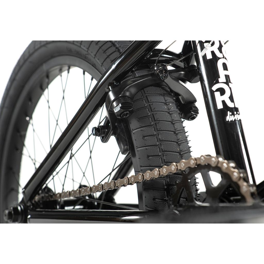 Close-up of the Division Reark 20 Inch Bike's rear wheel, highlighting the tire tread, spokes, chain, brake caliper, and part of its lightweight Hi-Tensile steel frame.