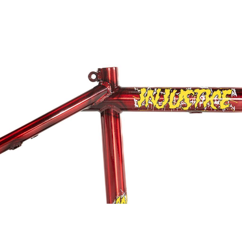 Close-up of a red Colony Injustice Frame (Tom Justice Signature), constructed from 4130 CrMo, featuring jagged yellow “INULSIRE” lettering on the top tube, isolated on a white background.