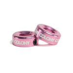 Two pink CNC-machined Colony Konka Bar Ends with white "COLONY" branding are stacked at an angle on a white background—essential BMX accessories for riders who want both durability and style.