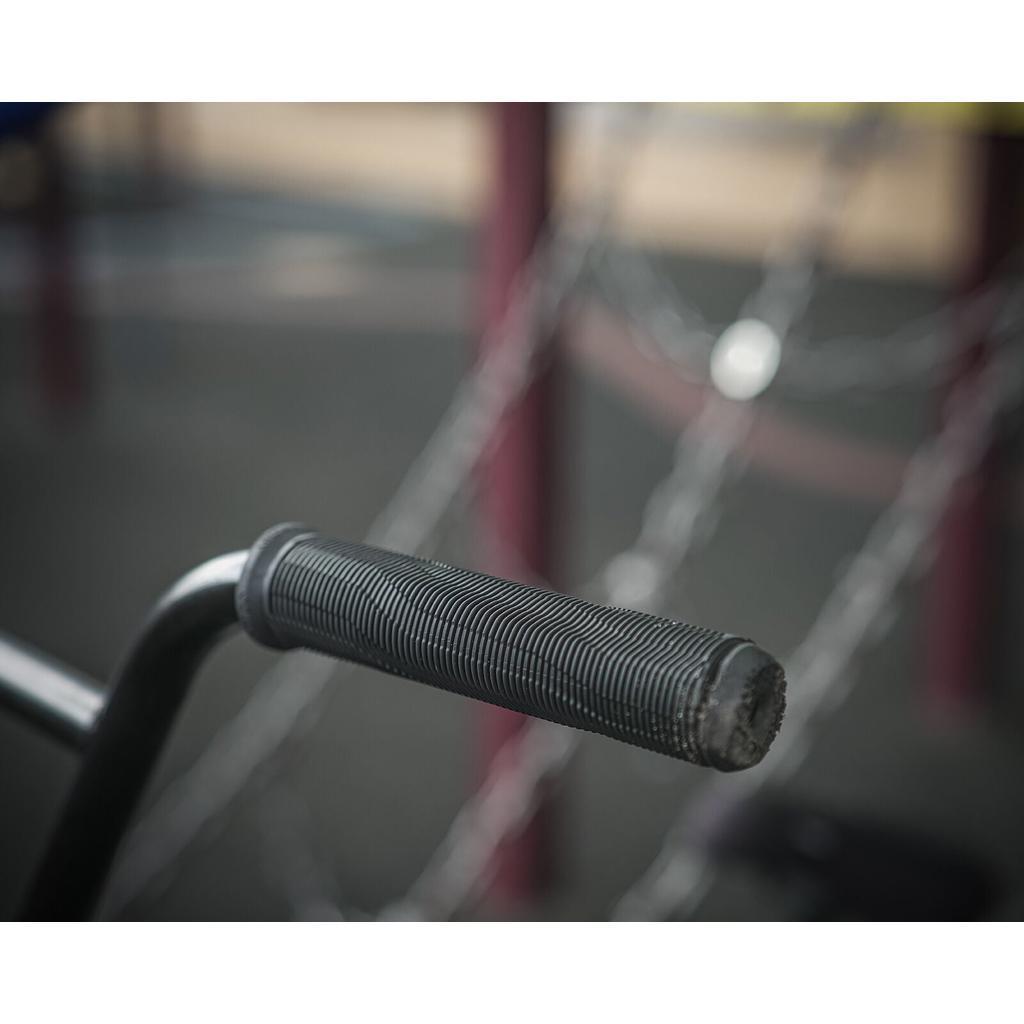 Close-up of textured black Colony Much Room Flangeless Grips with bar ends, set against a blurred playground background.
