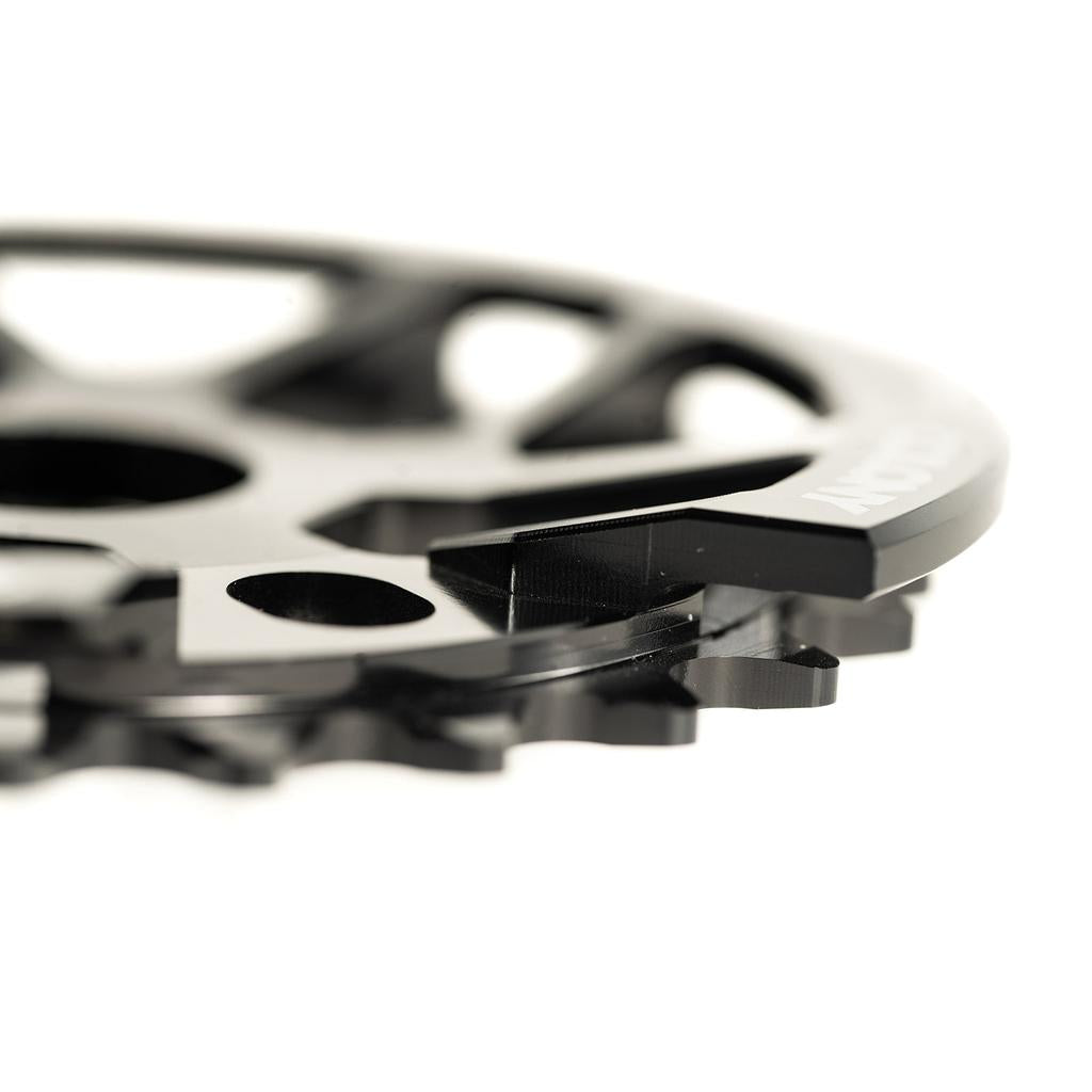 Close-up of the Colony Bish Guard Sprocket, a black BMX chainring with multiple teeth and holes, boasting a polished finish and intricate design, crafted from CNC machined aluminum.