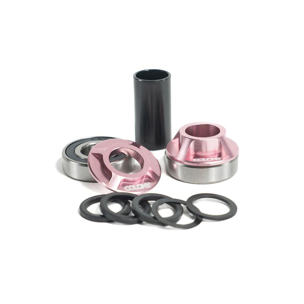 The Colony Bottom Bracket features lightweight 6061 alloy components: pink anodized cups, bearings, a black tube spacer, and several black washers, all displayed on a white background.