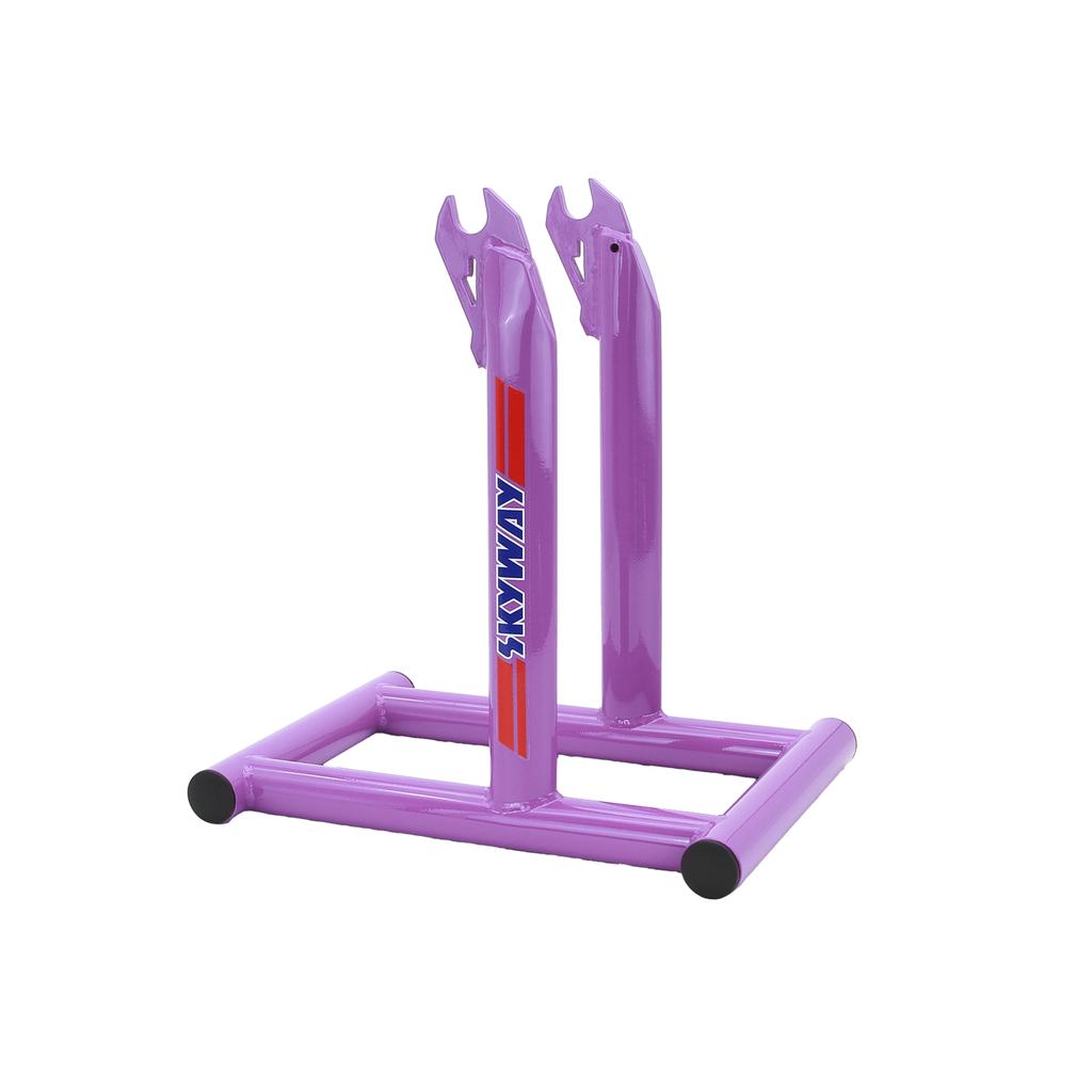 The Skyway Stolz Stand is a purple metal BMX bike stand with "SKYWAY" branding, designed to hold your bike upright by the rear wheel dropouts—ideal for displaying your Skyway TA Replica or other classic rides.