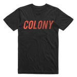 The Colony Momentum T-Shirt is a black tee made from 100% carded cotton, featuring "COLONY" in bold, red, slanted capital letters across the chest.