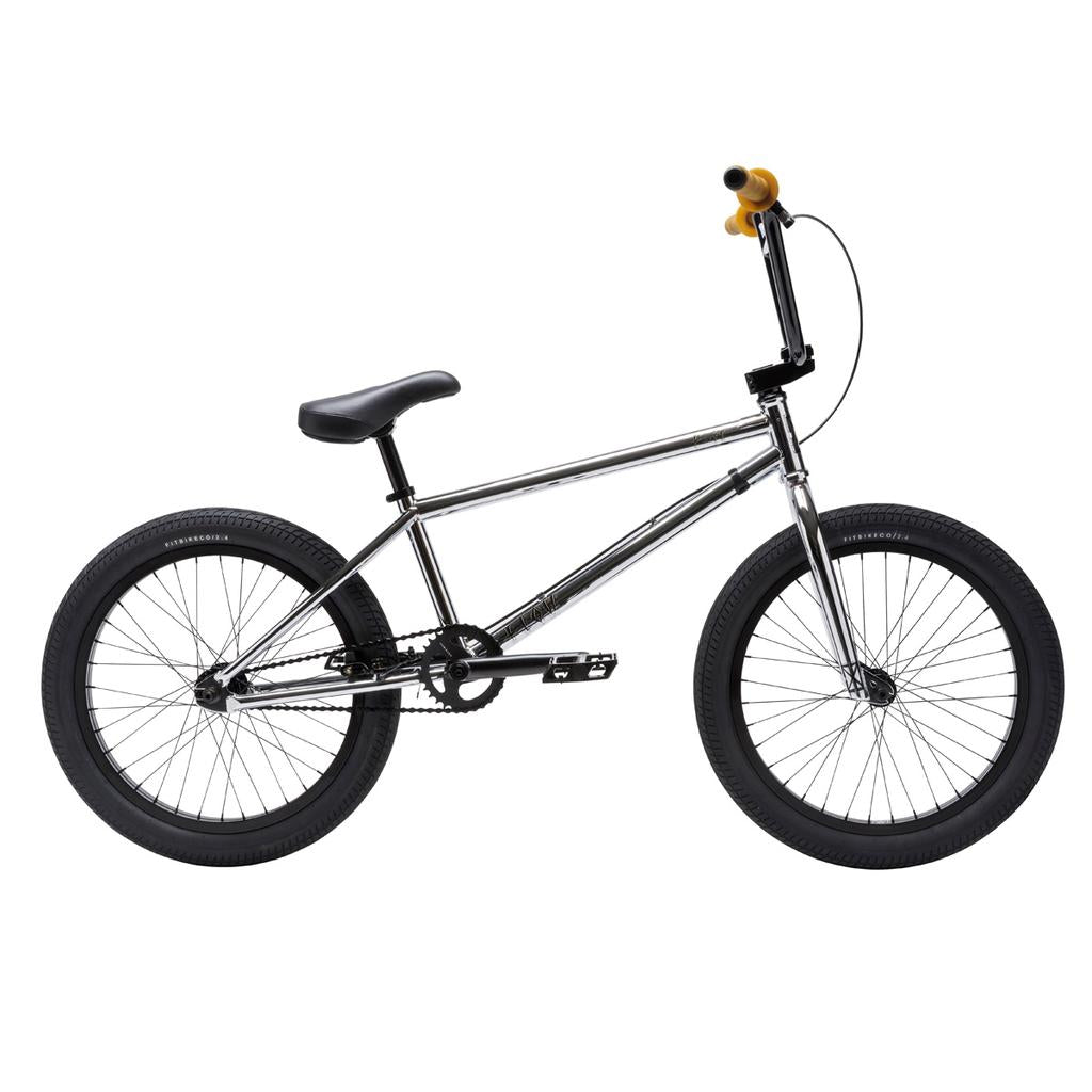 The Fit Bike Co Flow 20 Inch Bike features a silver frame, black tires and seat, yellow handlebar grips, and is shown in profile on a white background—ideal for trail or dirt jump riders.