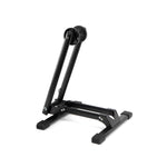The 6MIL BS-01 Bike Stand is a black, heavy-duty stand with foldable metal arms and rubber-tipped feet, shown upright against a white background.