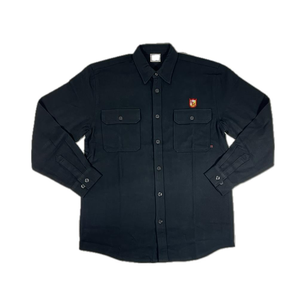 The S&M Shield Button Up Flannel Shirt is a heavyweight, long-sleeved black flannel made from 100% cotton. It features two chest pockets and a small red and yellow embroidered shield on the left pocket for style and durability.