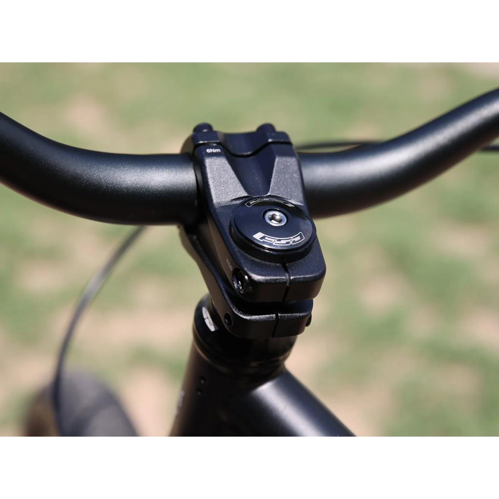 Close-up view of the Fairdale Hareraiser FX 26 Inch Bike's handlebar and stem assembly, showcasing a visible FSA top cap and 4130 chromoly construction, photographed outdoors.