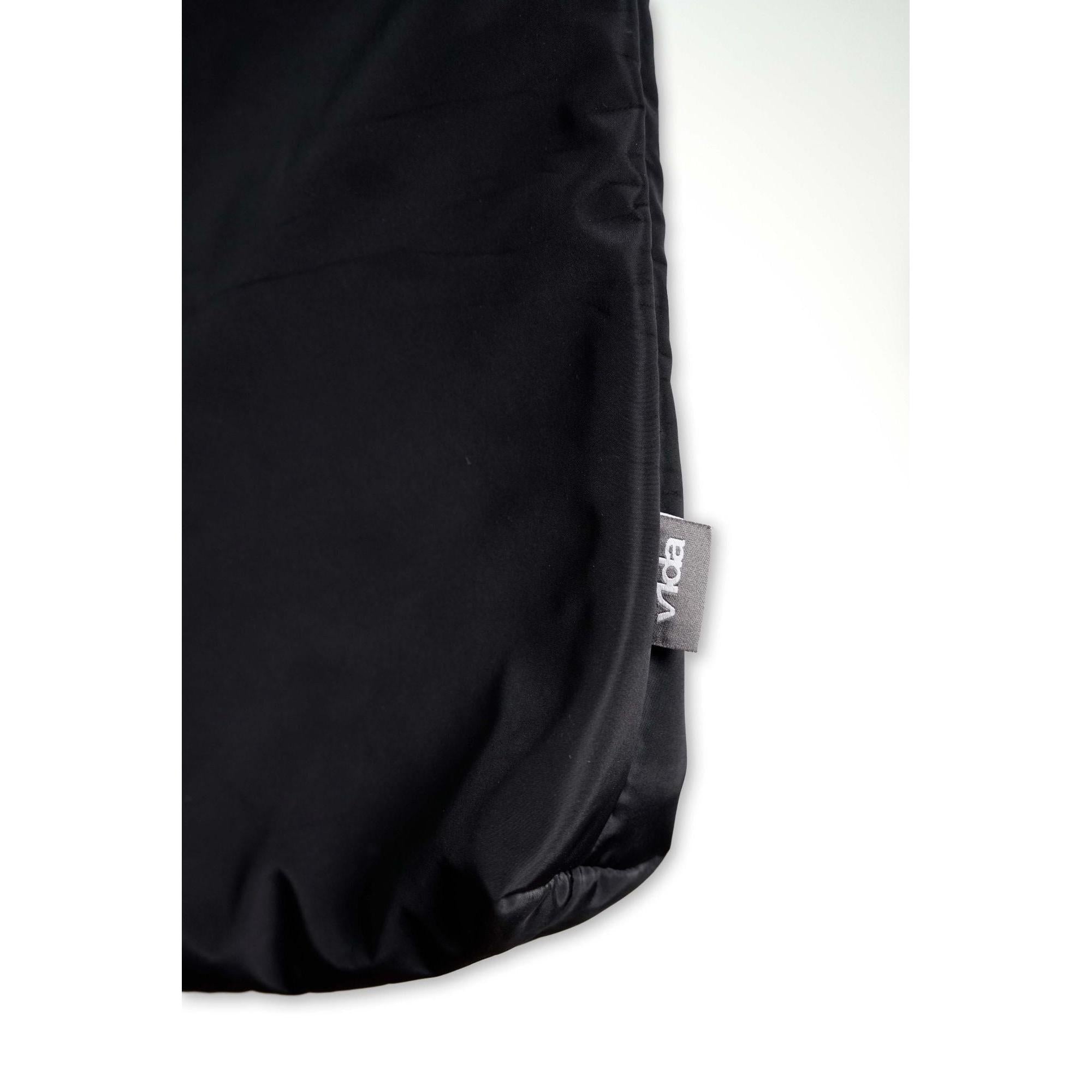 A close-up of the V1da Everything Messenger Bag, a black minimalist design with a small gray "Voda" tag on the edge, displayed against a white background.