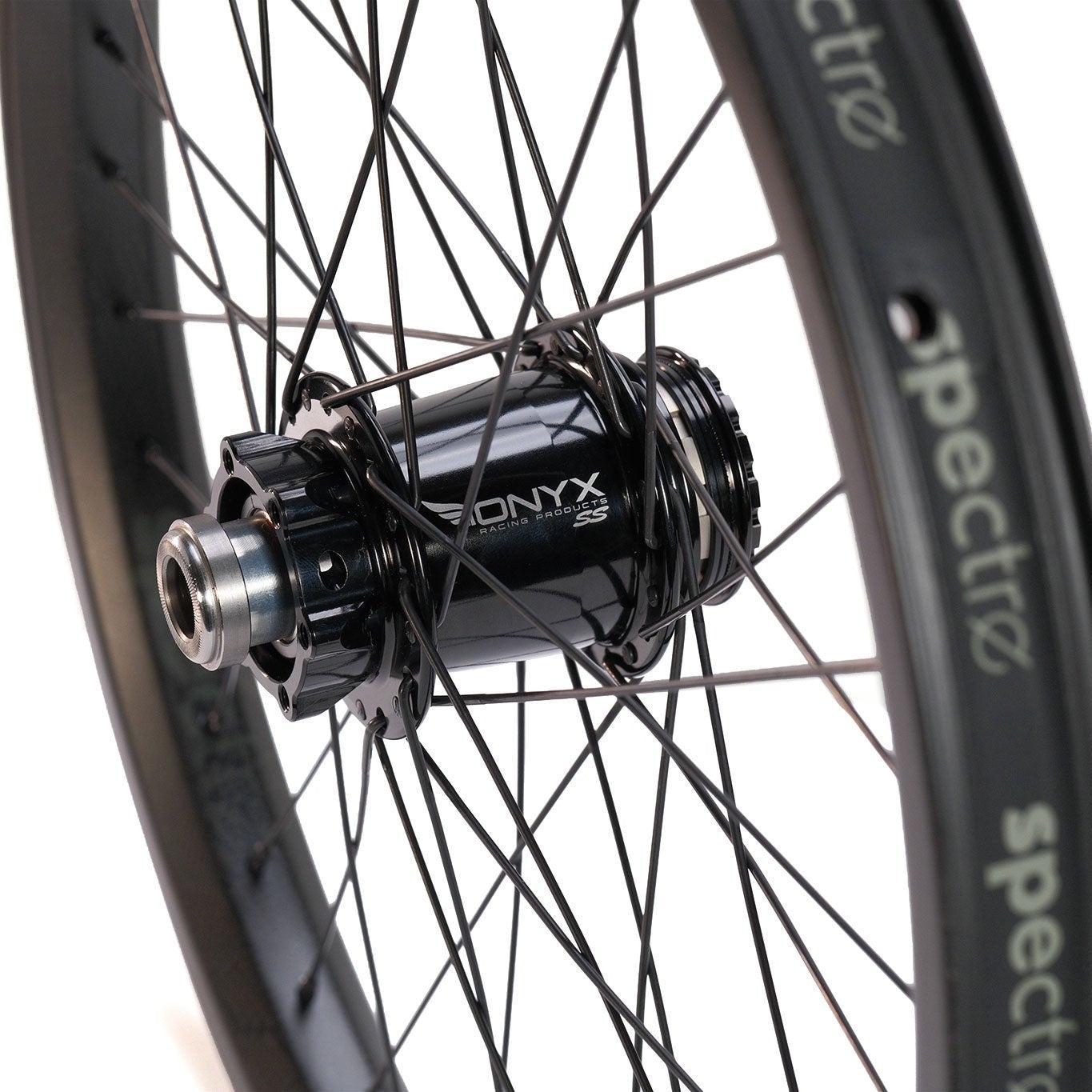 Close-up of a bicycle wheel with black spokes, Onyx hub, and “spectro” rim, highlighting the Spectre NME X Onyx Elite 20 Inch Disc Wheel Set (20mm/15mm), known for its strong BMX rims.