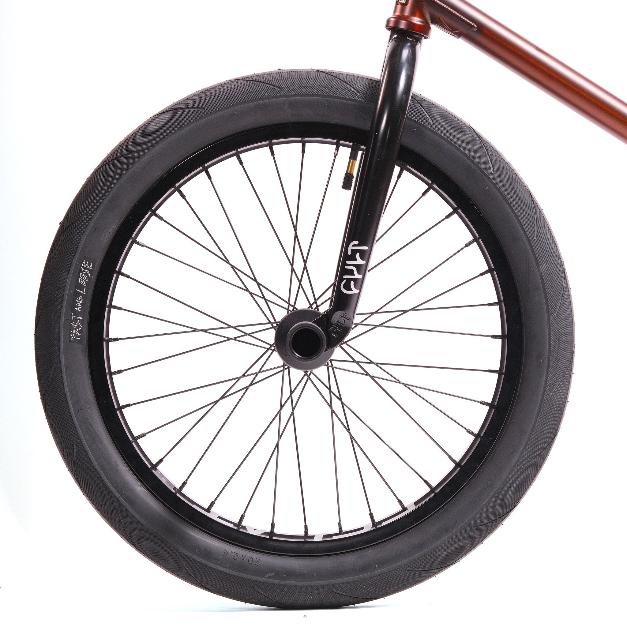 Close-up of the Cult Dak X Eclat Custom 'Pat Freyne Signature' BMX bike’s black front wheel with thick tire, black spokes, and a black fork featuring white "CULT" branding, shown against a plain white background.