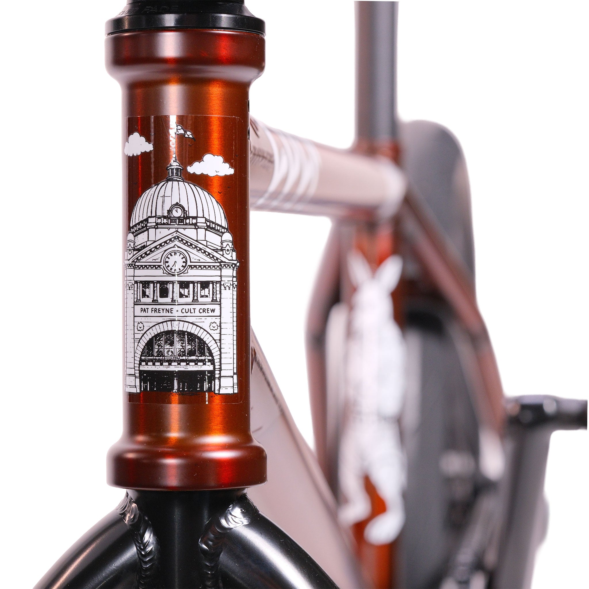 Close-up of a Cult Dak X Eclat Custom 'Pat Freyne Signature' BMX bike with a domed building illustration on the head tube and another Pat Freyne Signature graphic visible in the background.