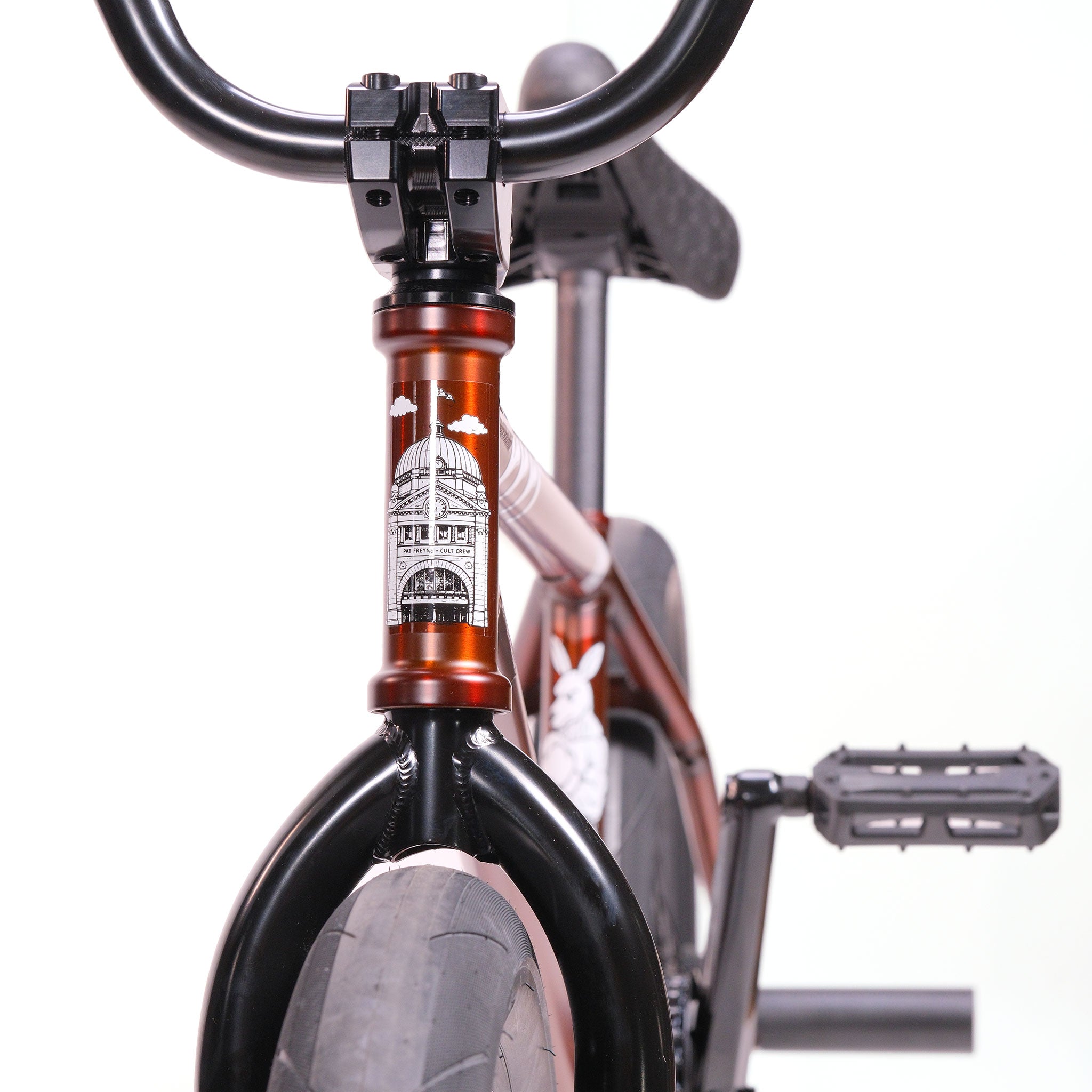 Close-up of the Cult Dak X Eclat Custom 'Pat Freyne Signature' BMX bike, showcasing signature handlebars, front wheel details, and an architectural illustration on the headset.