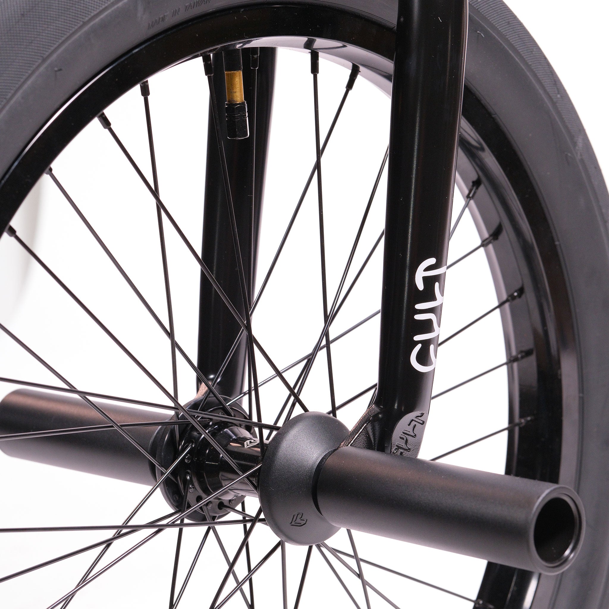 Close-up of a black BMX front wheel with spokes, axle peg, and "CULT" branding on the fork—featuring the Cult Dak X Eclat Custom 'Pat Freyne Signature'.