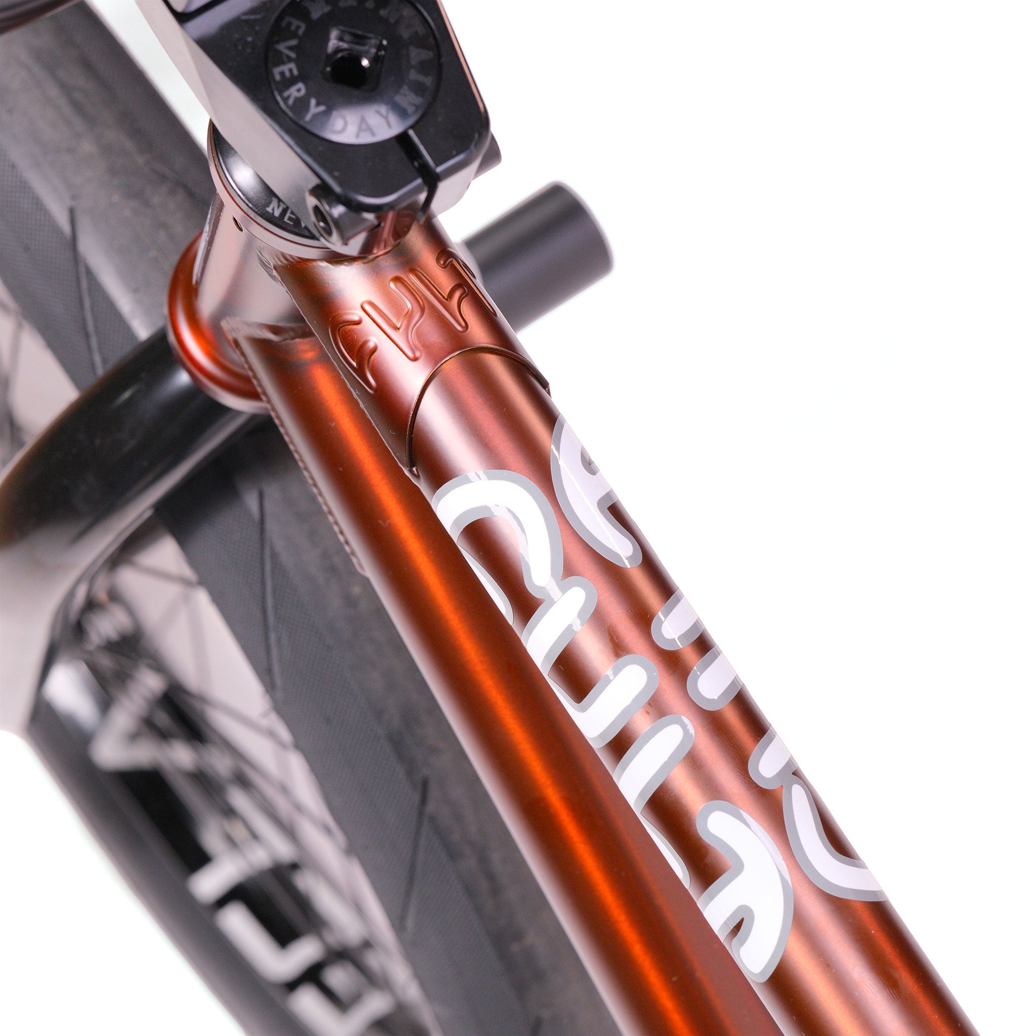 Close-up of the Cult Dak X Eclat Custom 'Pat Freyne Signature' BMX frame in metallic orange with white graphics, shown beside a black tire and stem clamp, highlighting its unique Pat Freyne Signature details.