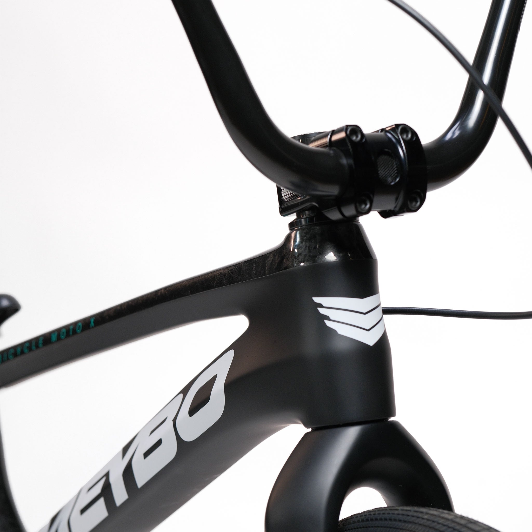 Close-up of a black bicycle frame and handlebars, showcasing a white decal and front brake cable against a plain white background. The sleek design highlights premium BMX parts, reminiscent of the Meybo HSX Carbon Pro XXL Race Bike found on high-performance race tracks.