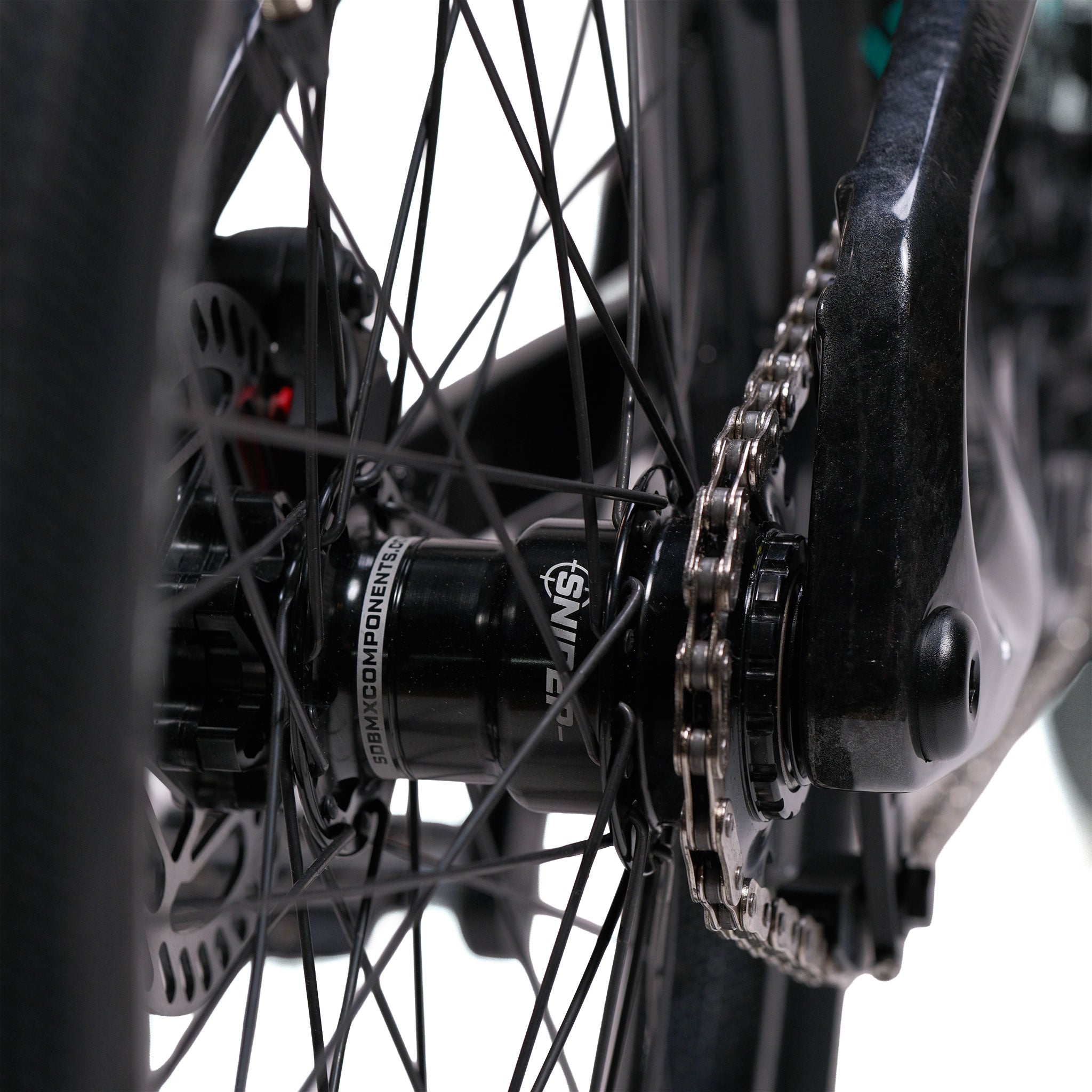 Close-up of a bicycle's rear wheel hub, showing the spokes, chain, and part of the brake rotor against a white background. The setup is featured with a Meybo HSX Carbon Pro XXL Race Bike for enhanced performance and durability.