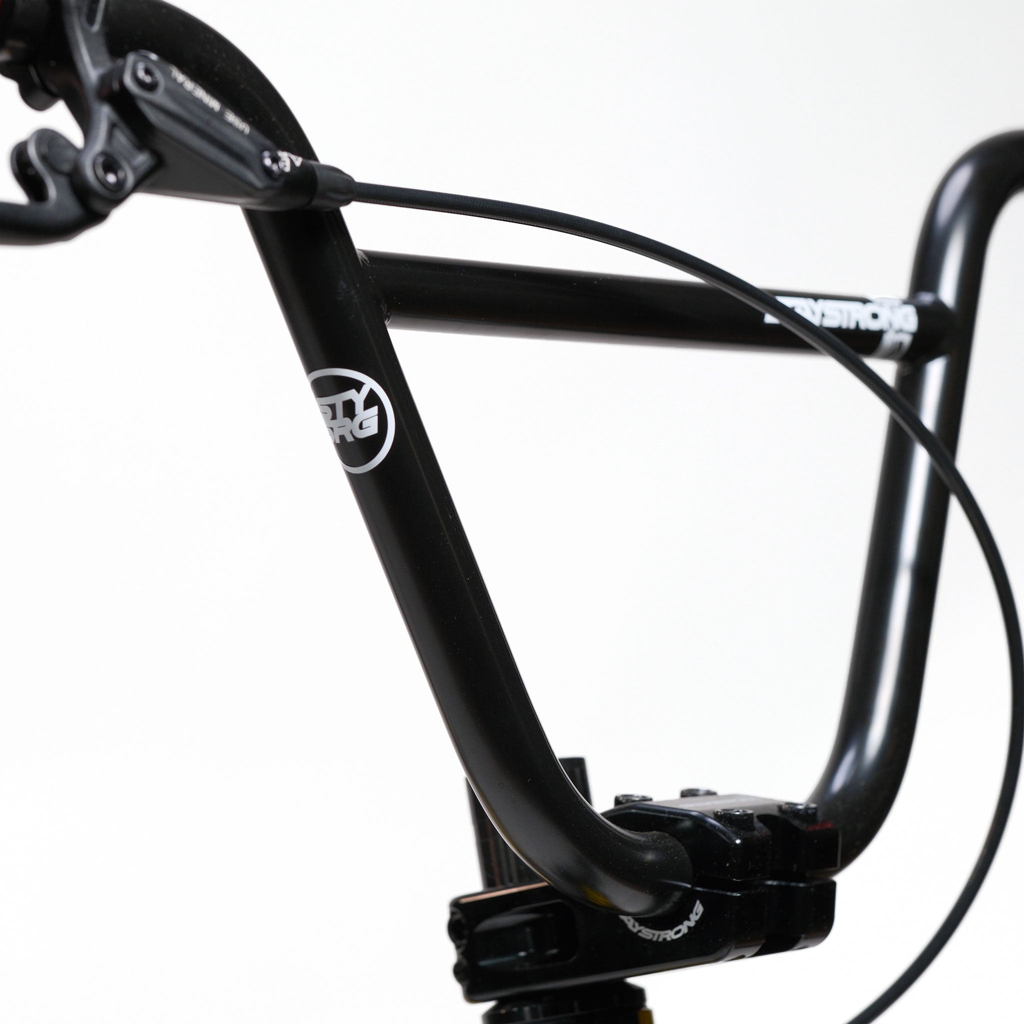 Close-up of a black bicycle handlebar with cables and brake lever against a plain white background, highlighting the precision engineering featured in custom race bikes like the Stay Strong V5.1 Pro XXXL Race Bike.
