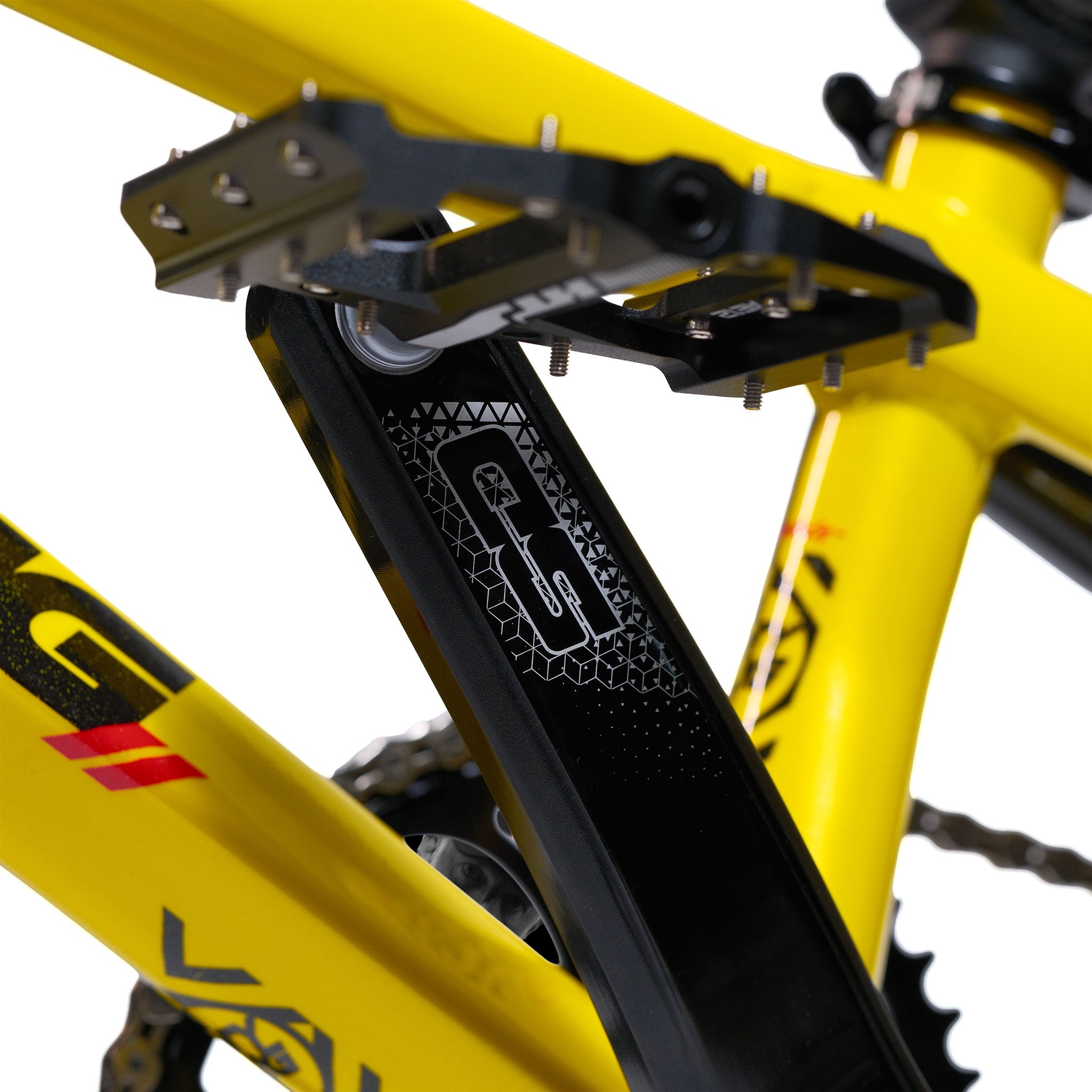 Close-up of a black bicycle crank arm and pedal attached to the yellow Stay Strong V5.1 Pro XXXL Race Bike aluminium frame, highlighting detailed branding and part of the custom race bike’s drivetrain.