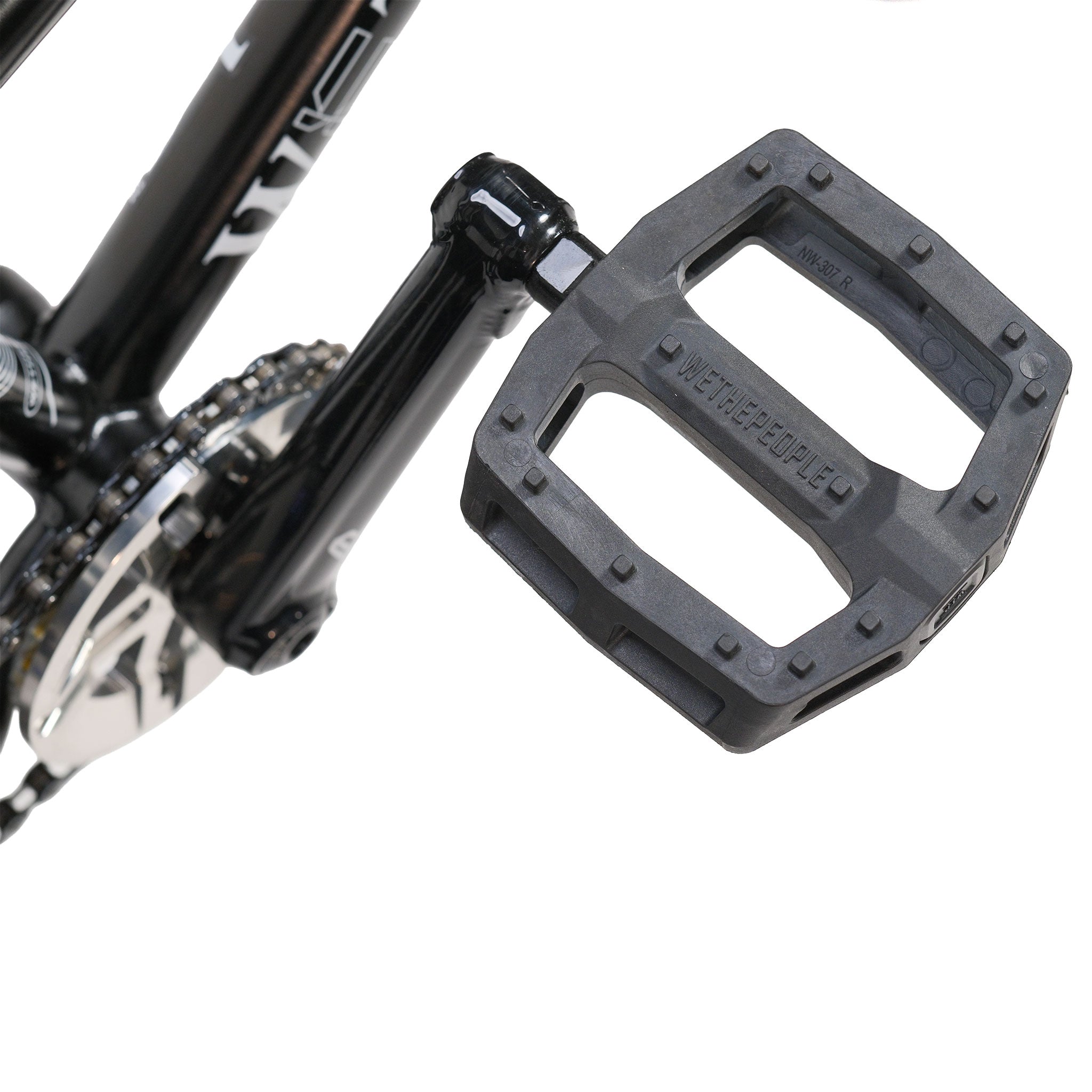 Close-up of a black bicycle pedal attached to the crank arm on the Wethepeople Prodi-G-Unit 18 Inch Custom Bike, with part of the chainring and chain visible in the background.