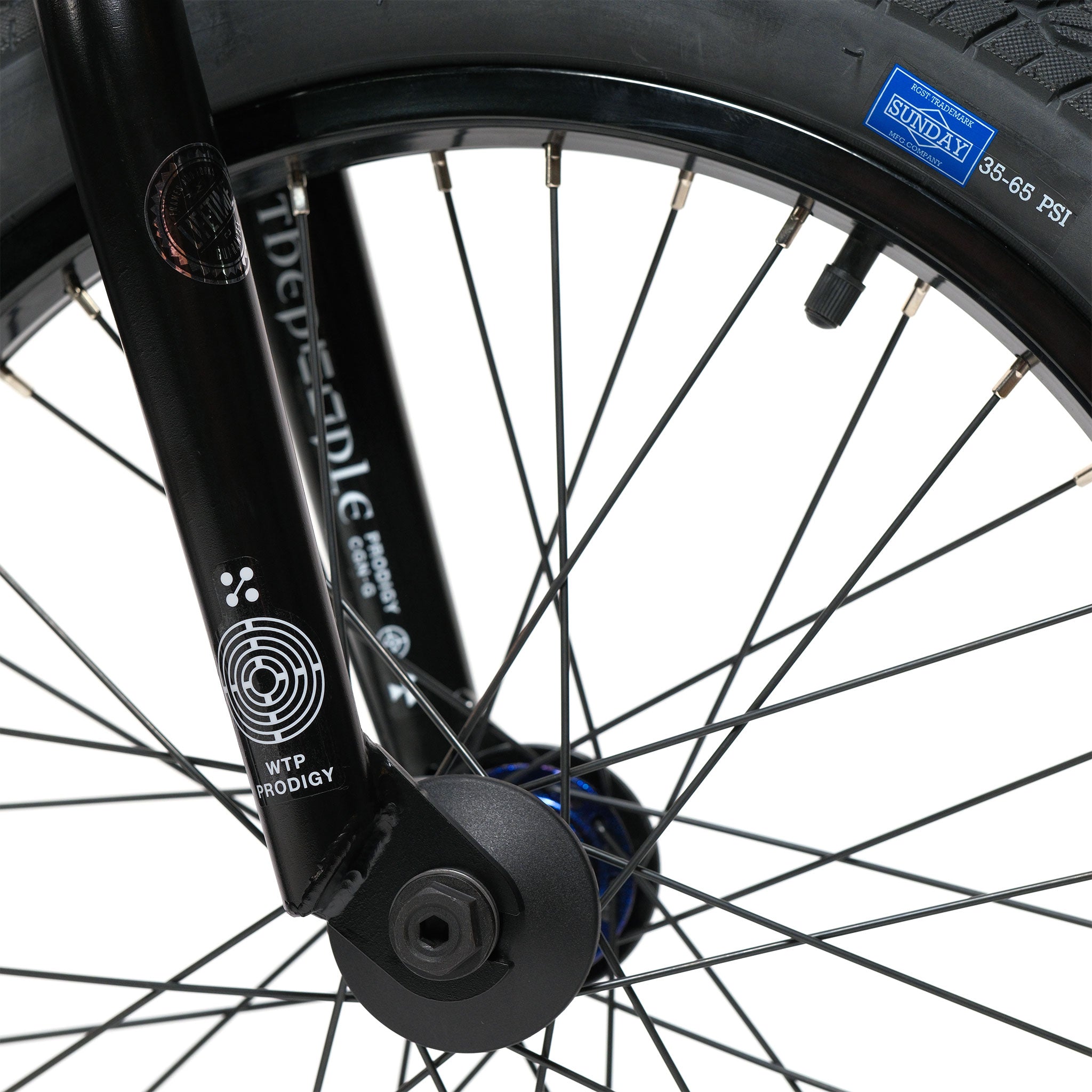Close-up of the Wethepeople Prodi-G-Unit 18 Inch Custom Bike’s front wheel featuring black spokes and a black fork labeled “WTP PRODIGY.” The tire, branded “SUNDAY,” displays a recommended pressure range of 35–65 PSI. Eclat components are part of what gives the Prodi-G-Unit 18 its high-quality build and performance.