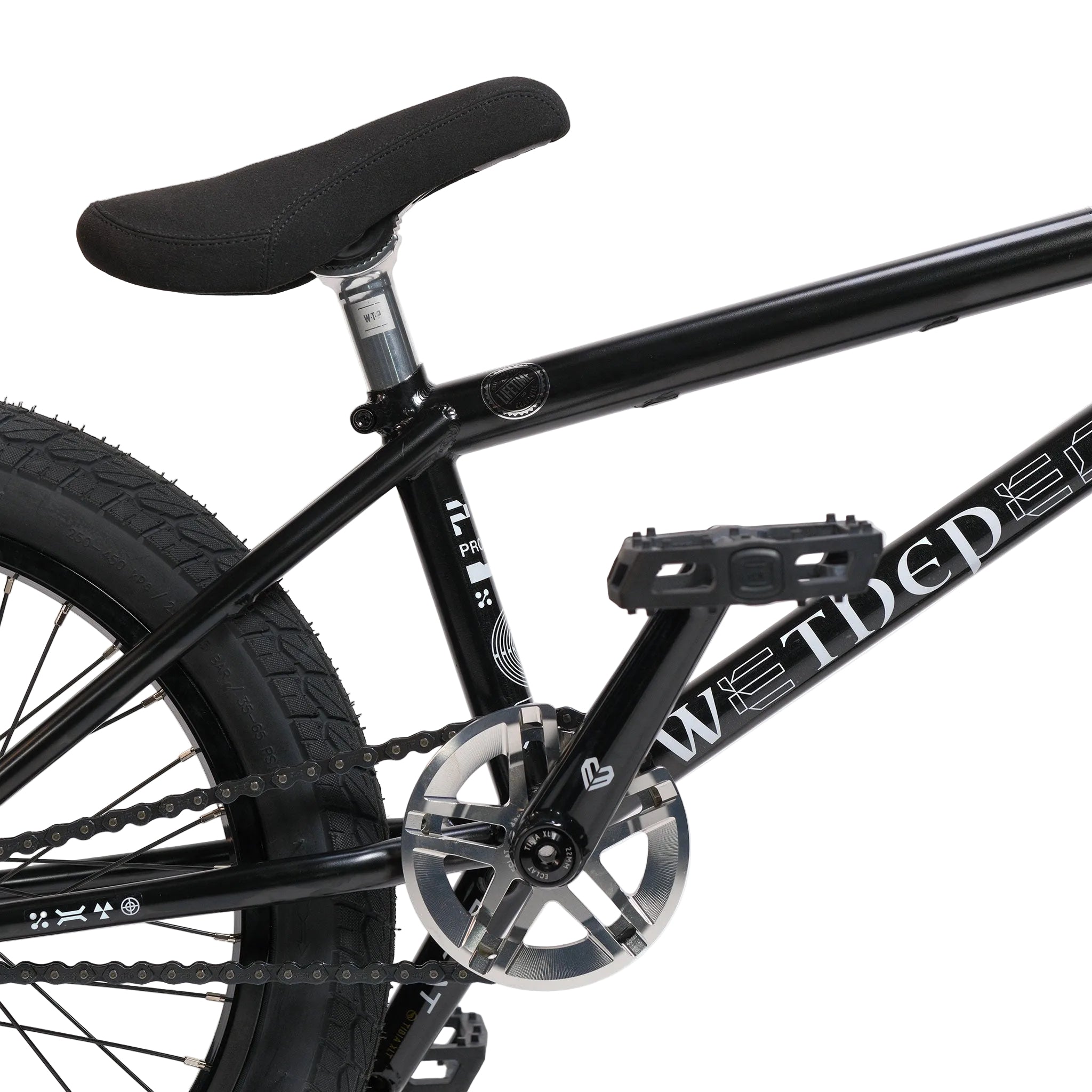 Close-up of a black BMX bike’s seat, pedal, chain, and rear wheel against a plain white background. The brand name “WETHEPEOPLE” is visible on the bike frame, highlighting this Wethepeople Prodi-G-Unit 18 Inch Custom Bike equipped with quality Eclat parts.