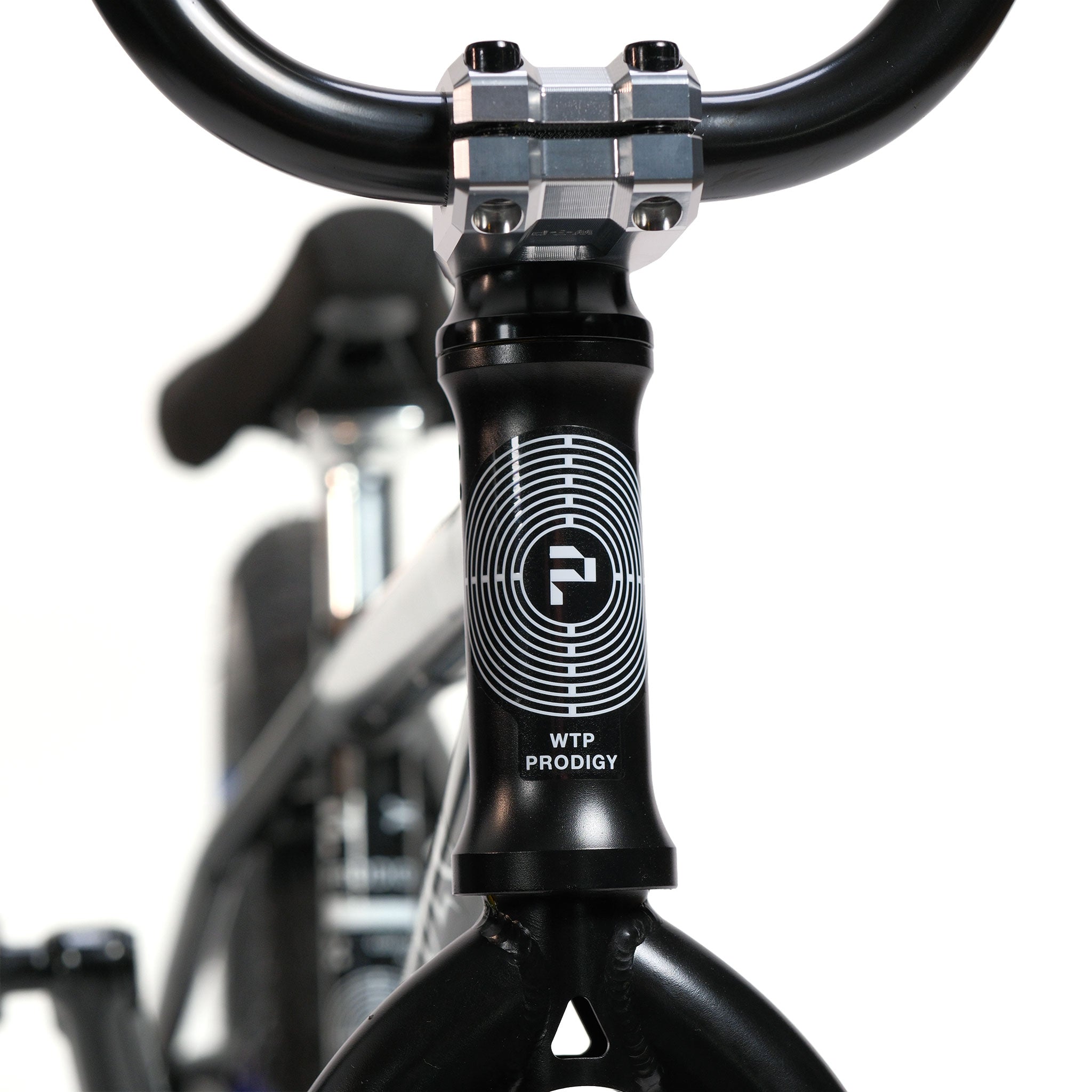 Close-up of a black BMX bike’s front with “WTP PRODIGY” and circular logo on the head tube, featuring handlebars and part of the frame against a white background. This Wethepeople Prodi-G-Unit 18 Inch Custom Bike showcases quality Eclat parts for top performance.