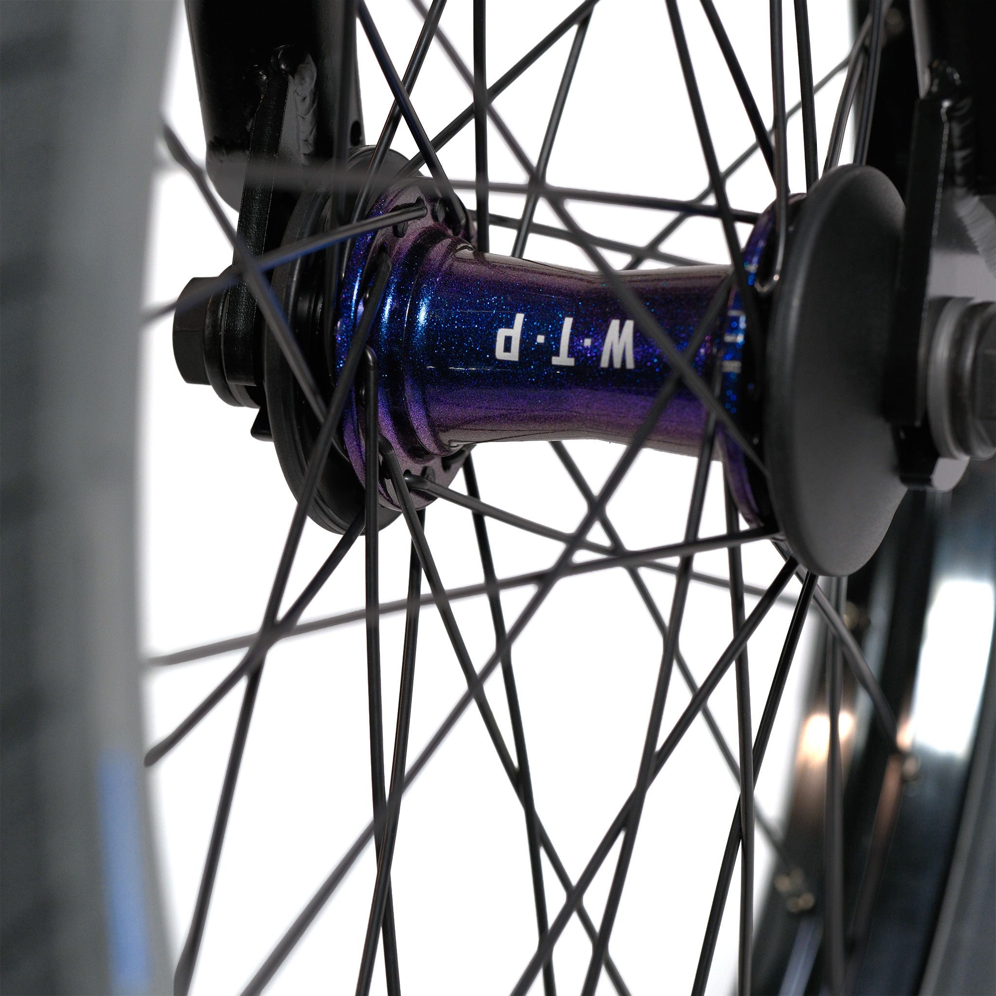 Close-up of the Wethepeople Prodi-G-Unit 18 Inch Custom Bike’s wheel hub with black spokes and a metallic blue center labeled “WTP,” featuring high-quality Éclat components.