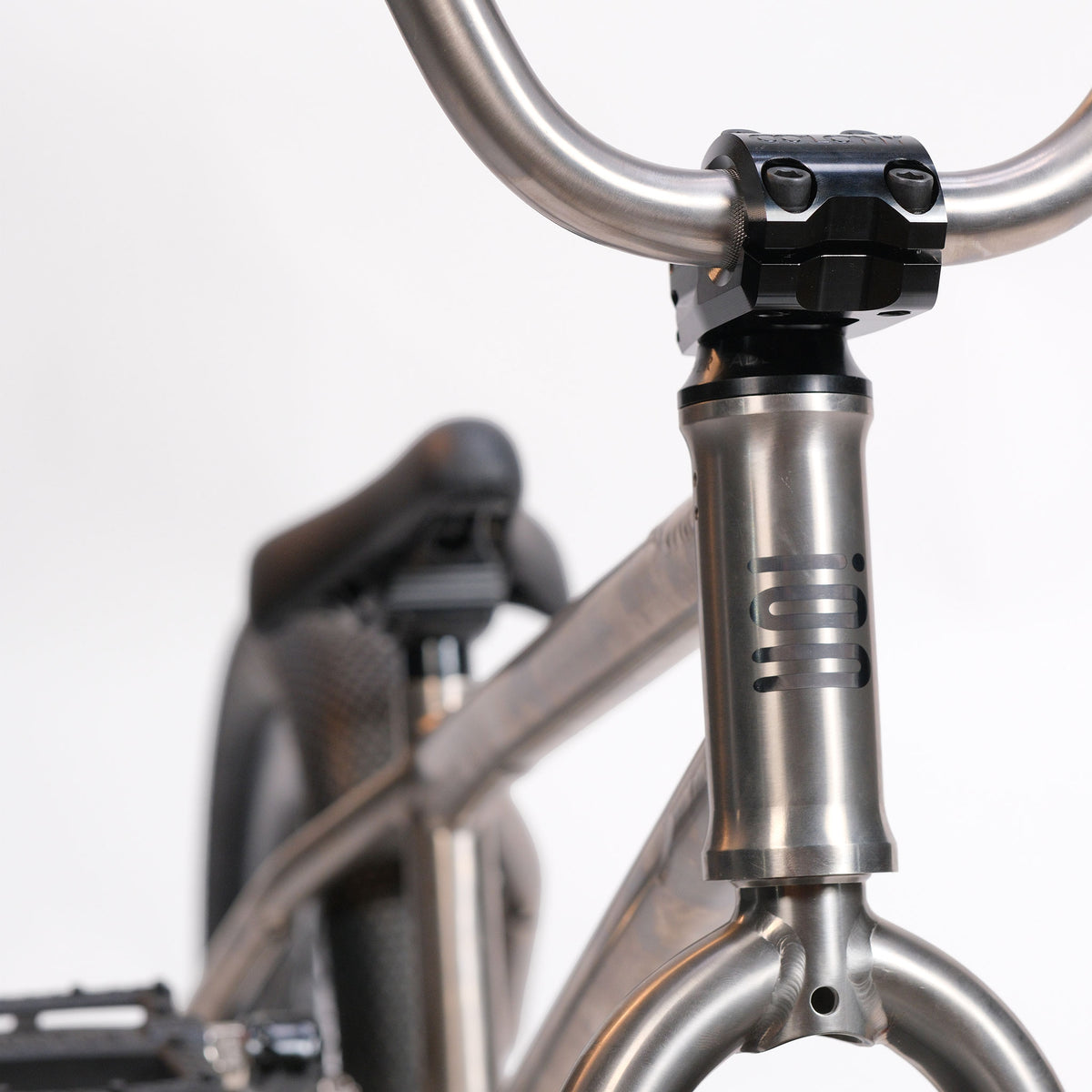 Close-up of the ION BMX Ti16 Custom Titanium 16 Inch Bike, highlighting its lightweight silver titanium frame and handlebars, with black saddle and pedals visible, set against a plain white background.