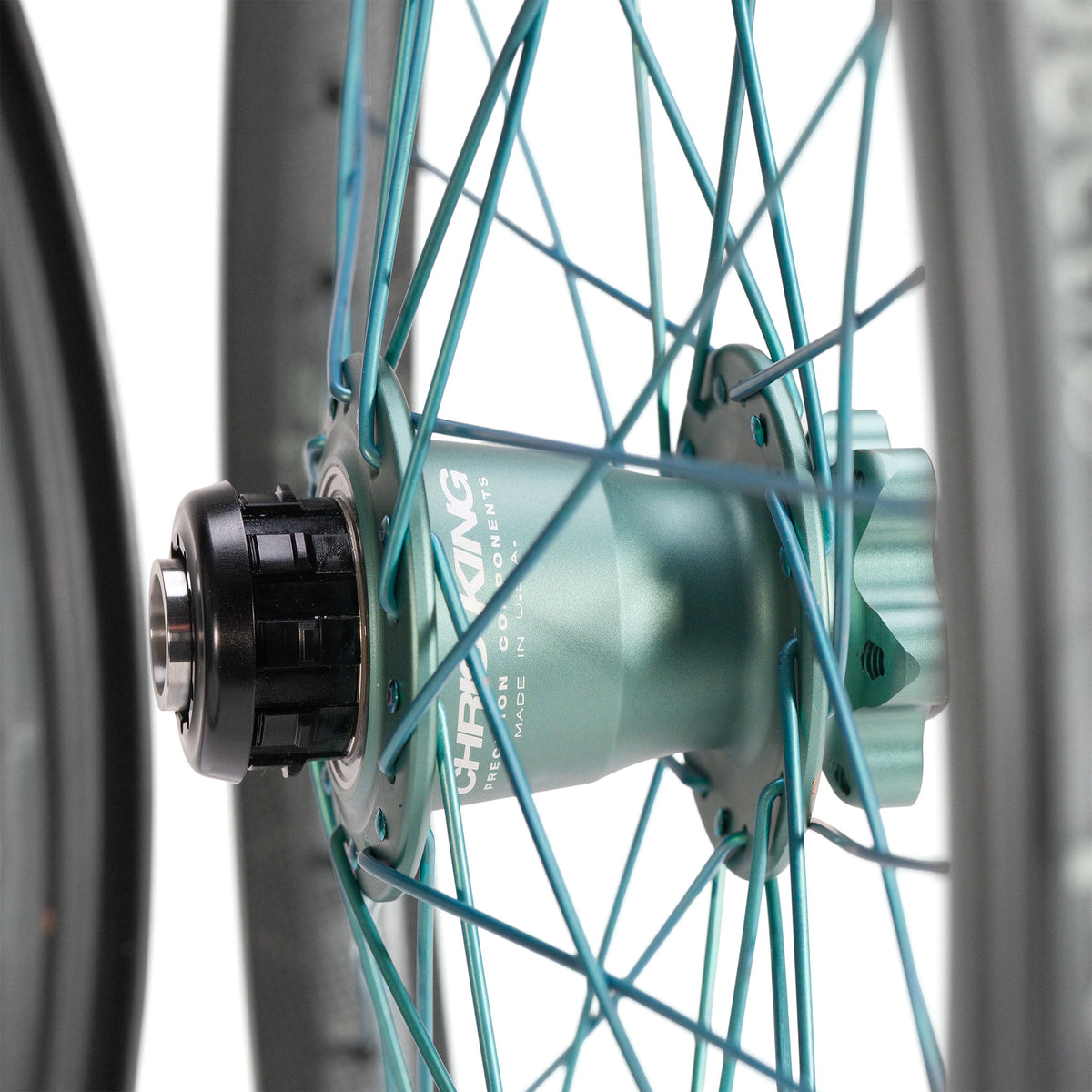 Teal BMX race wheel hub from a Chris King X Spectre NME Custom 20inch Wheel Set, featuring matching teal titanium spokes and a black cassette body.