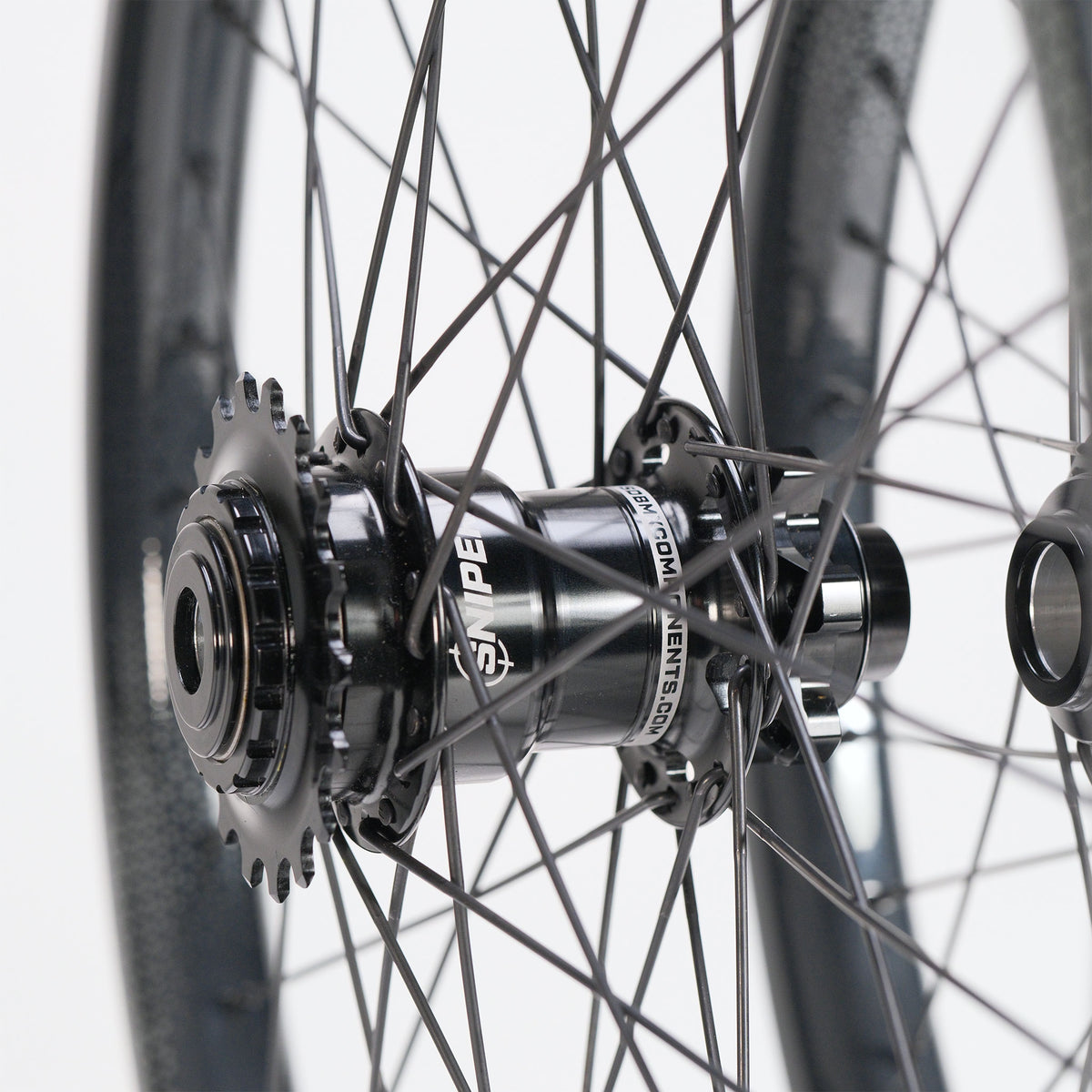 Close-up of the SD-X Sniper Evo Pro x SD-X M58 V2 20inch Wheel Set hub on a bicycle wheel with a cassette sprocket and black spokes.