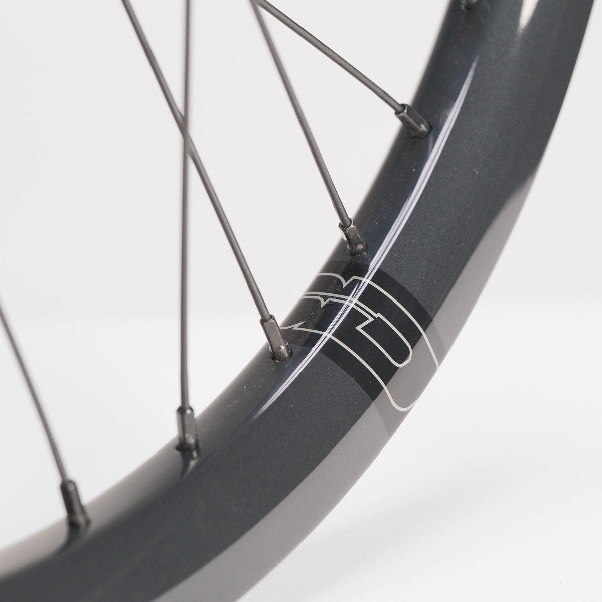 Close-up of a dark grey SD-X Sniper Evo Pro x SD-X M58 V2 20inch Wheel Set rim with thin metal spokes and a graphic logo.