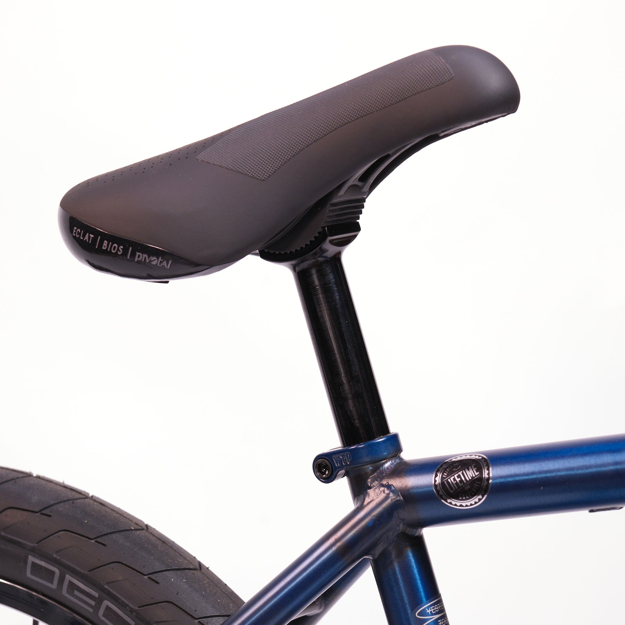 Close-up of a black bicycle seat on a blue Wethepeople Tomorrow X TA Custom build BMX bike, showing part of the seat post, rear wheel, and tire.