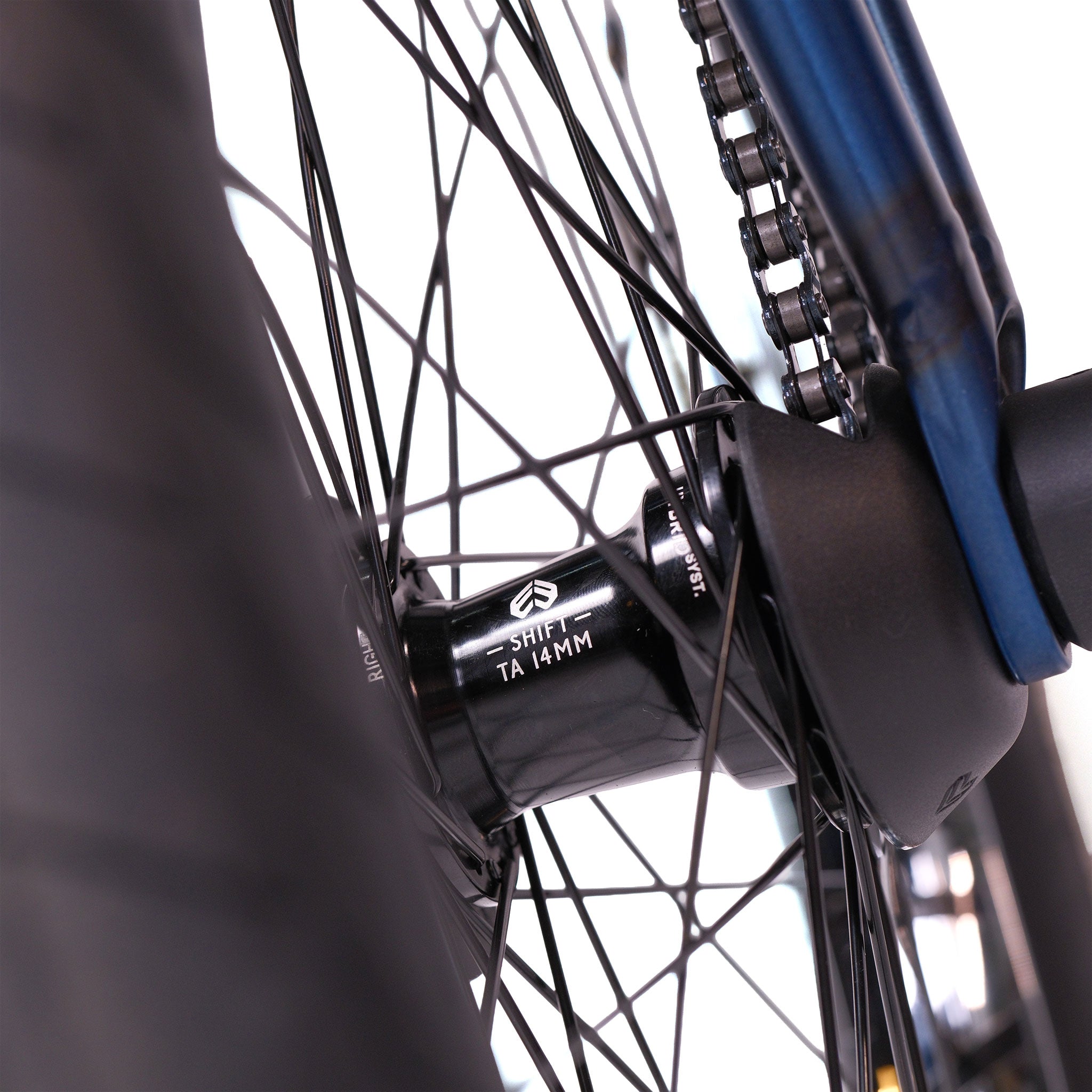 Close-up of the rear wheel hub labeled "SHIFT TA 14MM" with spokes, tire, and chain—featured on the Wethepeople Tomorrow X TA Custom build BMX bike, against a white background.