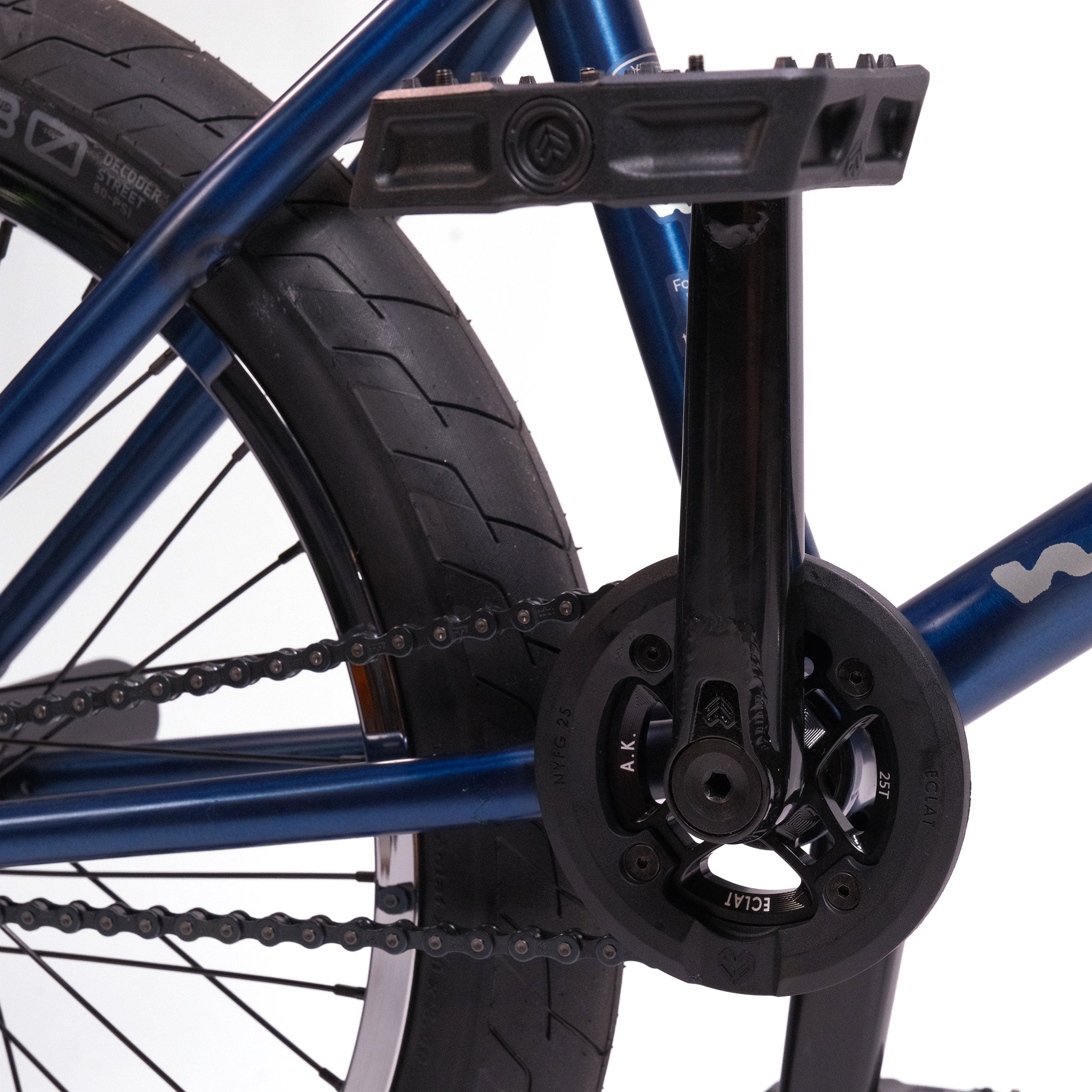 Close-up of the crankset, chainring, and pedal on a Wethepeople Tomorrow X TA Custom build BMX bike, showing part of the blue frame, rear tire, and visible chain.