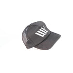 The LUXBMX Flag Trucker Cap features a black mesh back, solid front with white "LWK" lettering, and is made in Brisbane from recycled polyester. Shown on a plain white background.