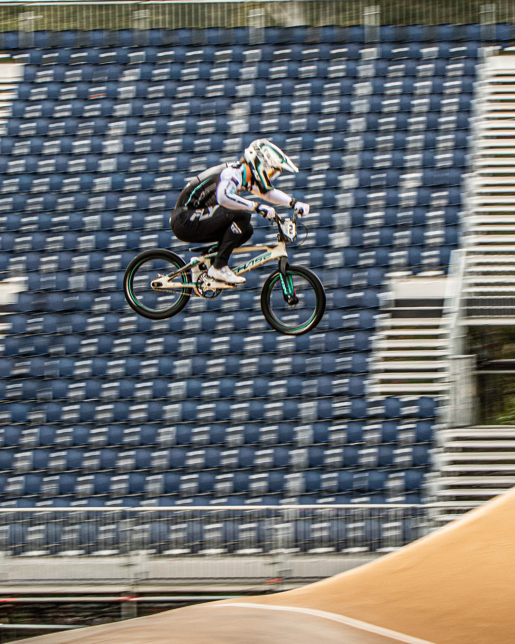 A BMX rider catches air on the Sleeman track during a UCI event, empty stadium seats behind—captured in the LUXBMX World's Race Photo Packages.