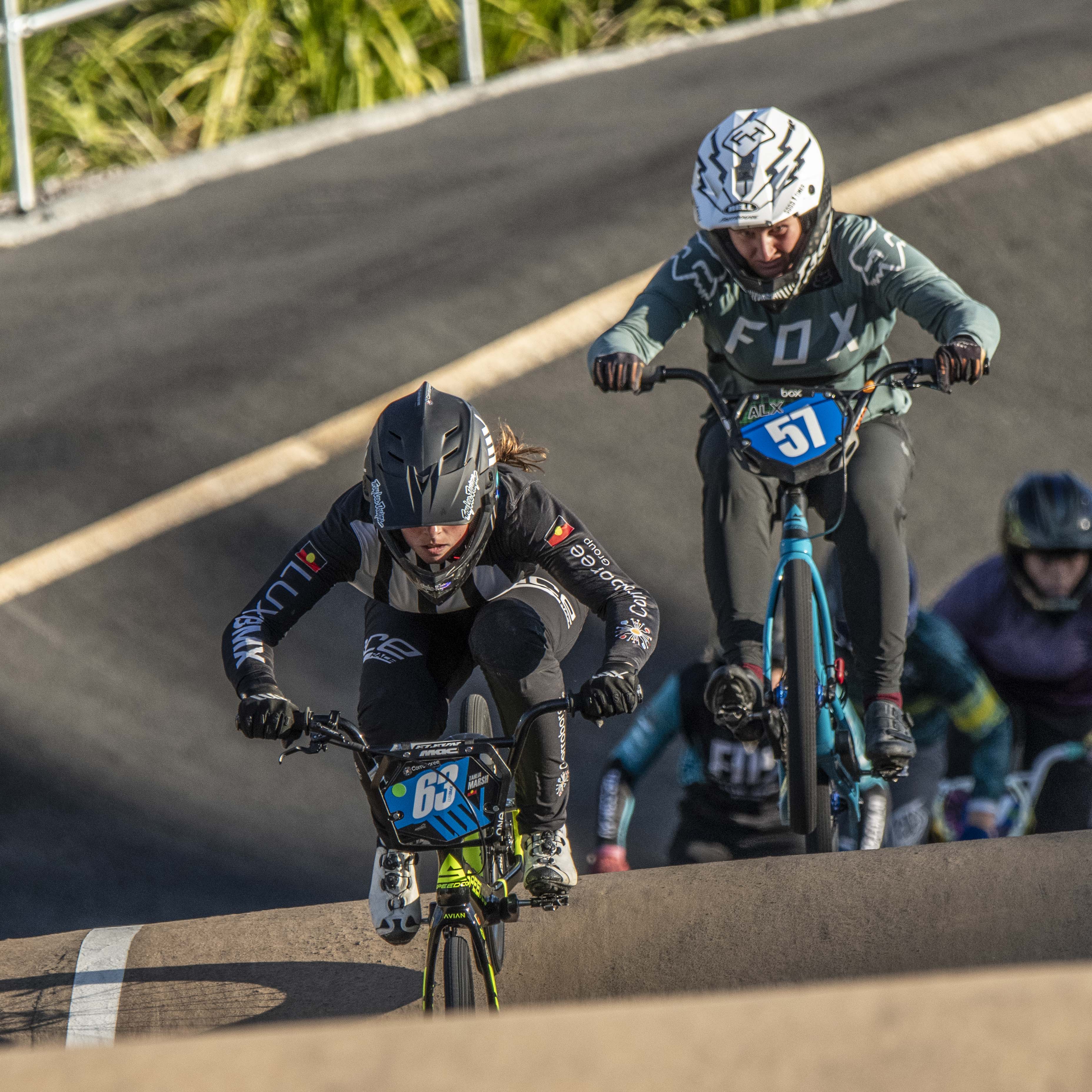 Two cyclists in full gear race on a BMX track for a National Championship spot, with number 68 leading and 57 close behind. Capture moments like these with the LUXBMX Race Photo Package.