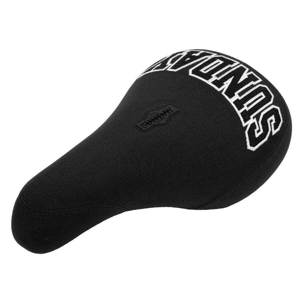 The Sunday Blockhead Pivotal Seat features textured black fabric, bold white collegiate-style "SUNDAY" branding across the back, and a small "Sunday" logo patch on top.