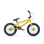 The Wethepeople Seed 16 Inch Bike showcases bold "WETHEPEOPLE" branding on its frame, featuring thick black tires and Salt Rookie Tubular Chromoly Cranks. Displayed from the side against a pristine white background, this vibrant yellow BMX shredder is a visual standout.
