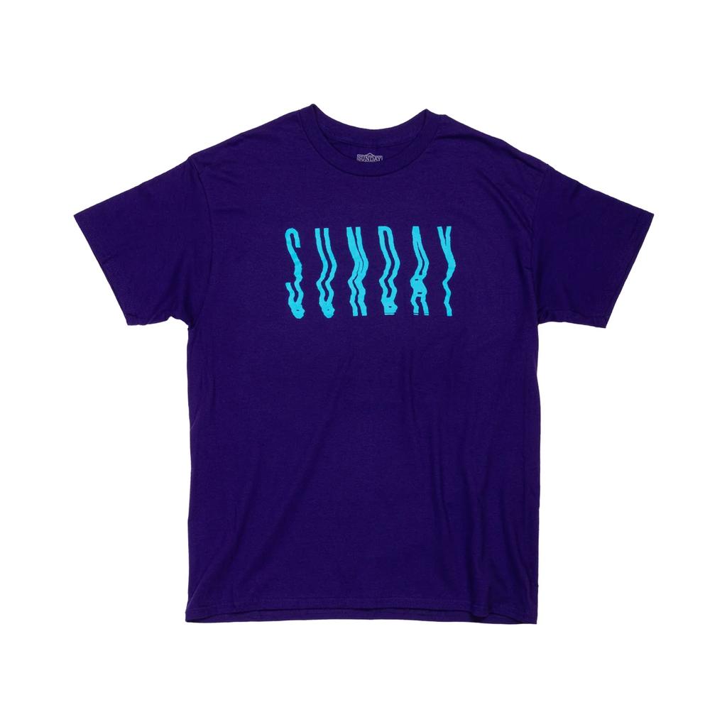 The Sunday High Wave T-Shirt features large, wavy light blue "SUNDAY" lettering on a plain purple tee, adding bold style to your casual look.