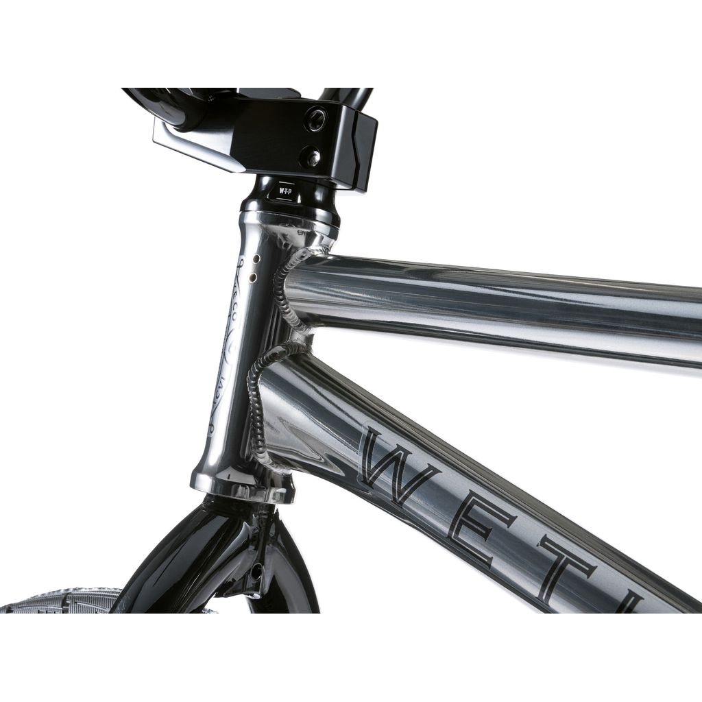 A close-up of a metallic frame with "WETHE" engraved, highlighting the front fork and handlebars—a true BMX masterpiece from the Wethepeople Envy 20 Inch Bike collection.
