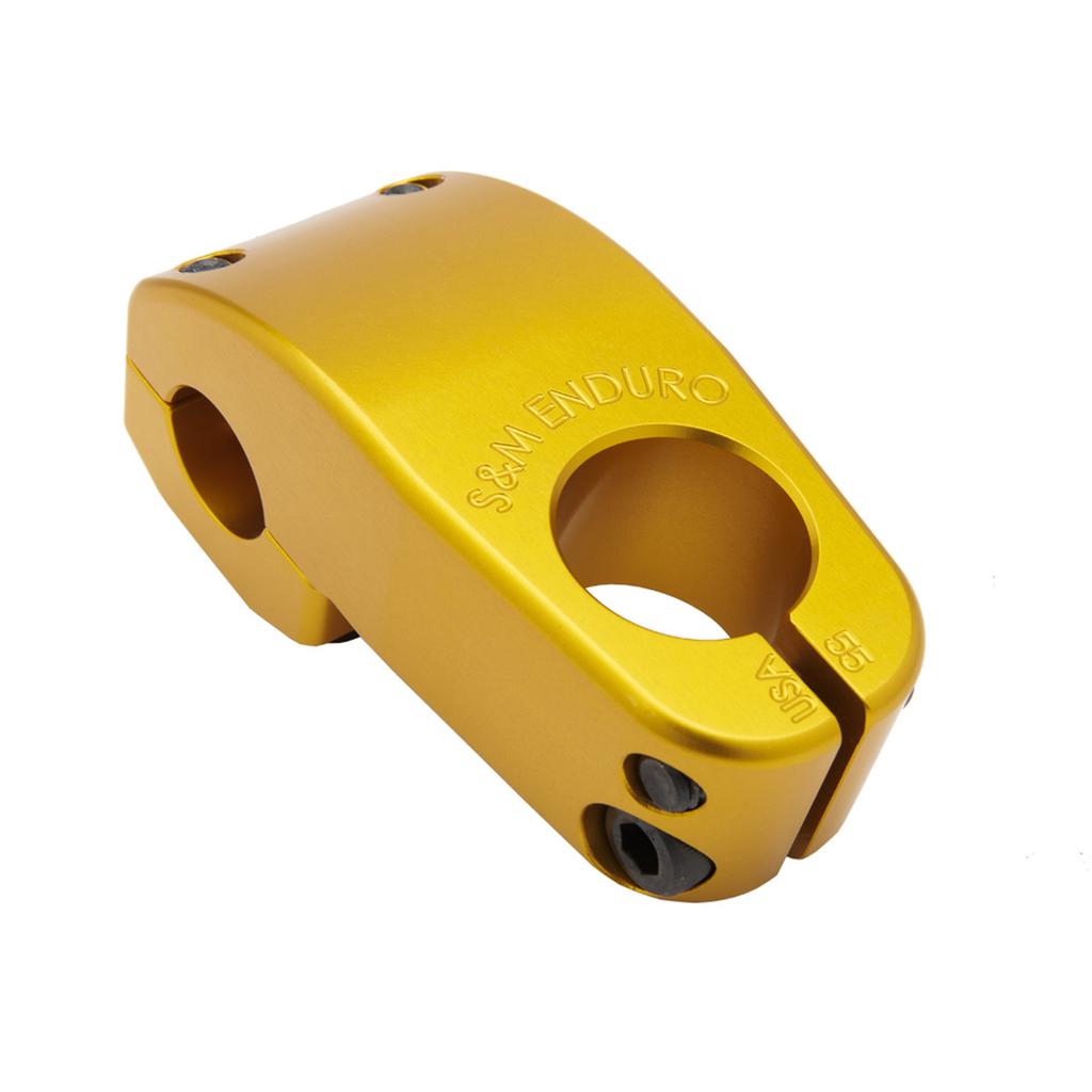 The S&M Enduro V2 Stem in gold features engraved branding, a top load design with front clamp, and visible bolt holes, shown on a white background.