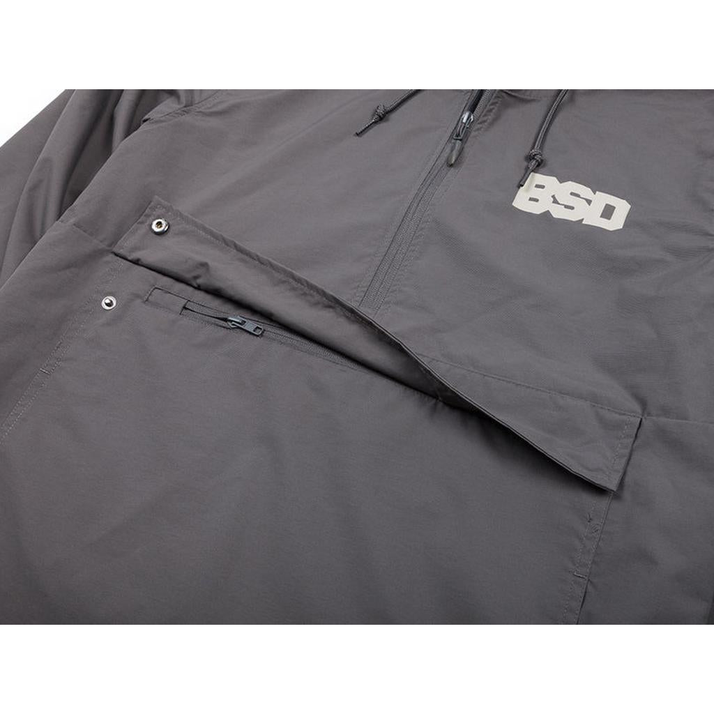 Close-up of the BSD Athletic 91 Windbreaker Jacket, a gray water-resistant nylon jacket with a zippered chest pocket, snap button pocket flap, and "BSD" in white on the upper chest.