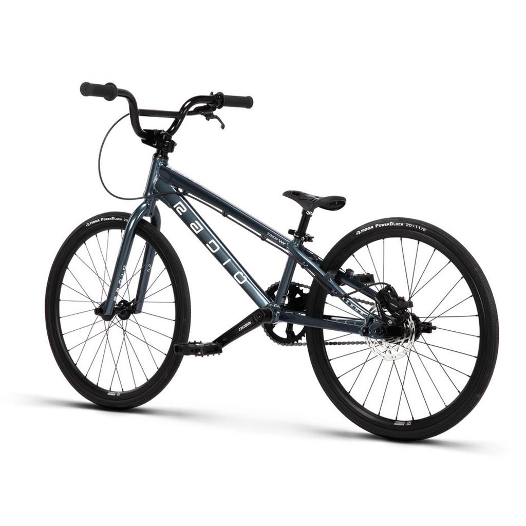 A Radio Xenon Junior Disc 20 Inch Bike in dark blue, featuring a hydroformed 6061-T6 alloy frame, black wheels with Tioga Power Block tyres, a slim seat, and a white logo, displayed from a rear side angle on a white background.