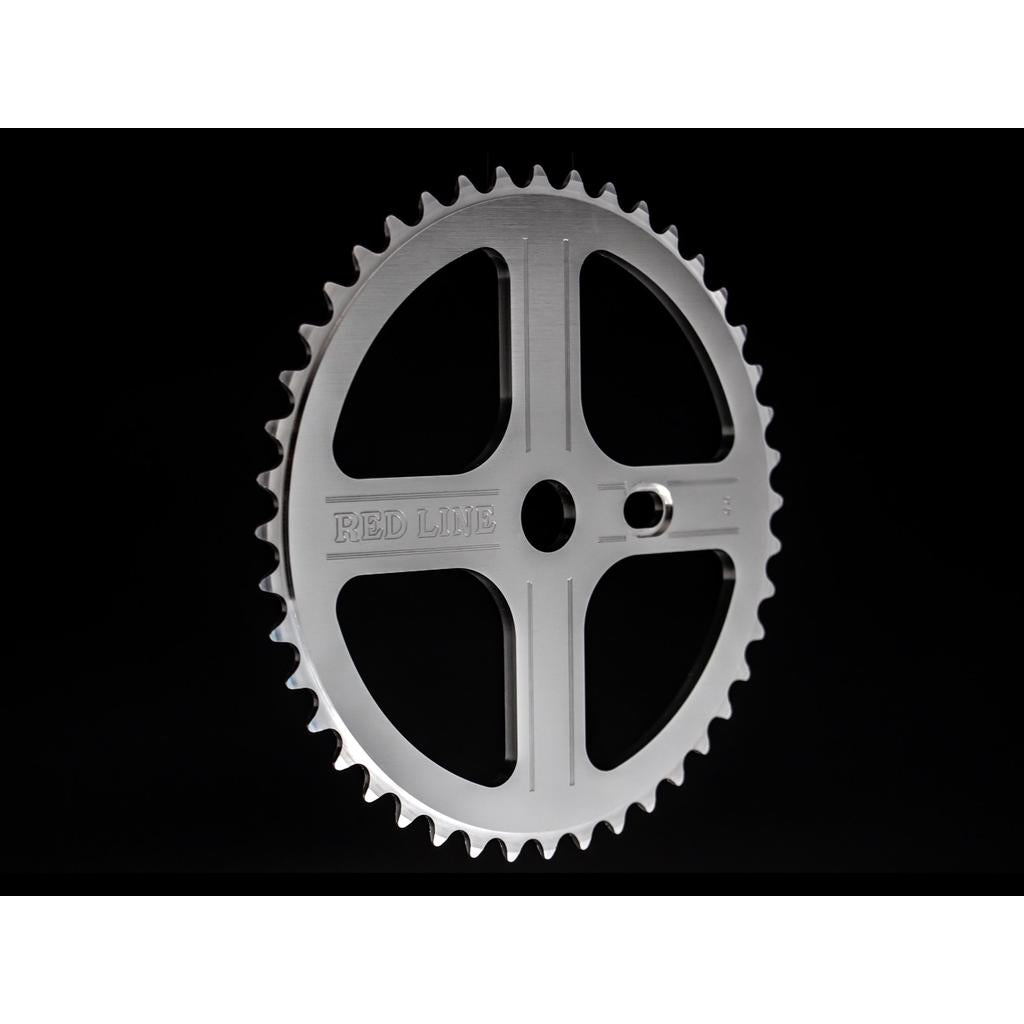 A silver metal chainring with 44 teeth from the 1980s, marked "RED LINE," designed for BMX racing and paired with the Redline Vintage Flight 401 Pinchless Crank Set, is shown against a black background.