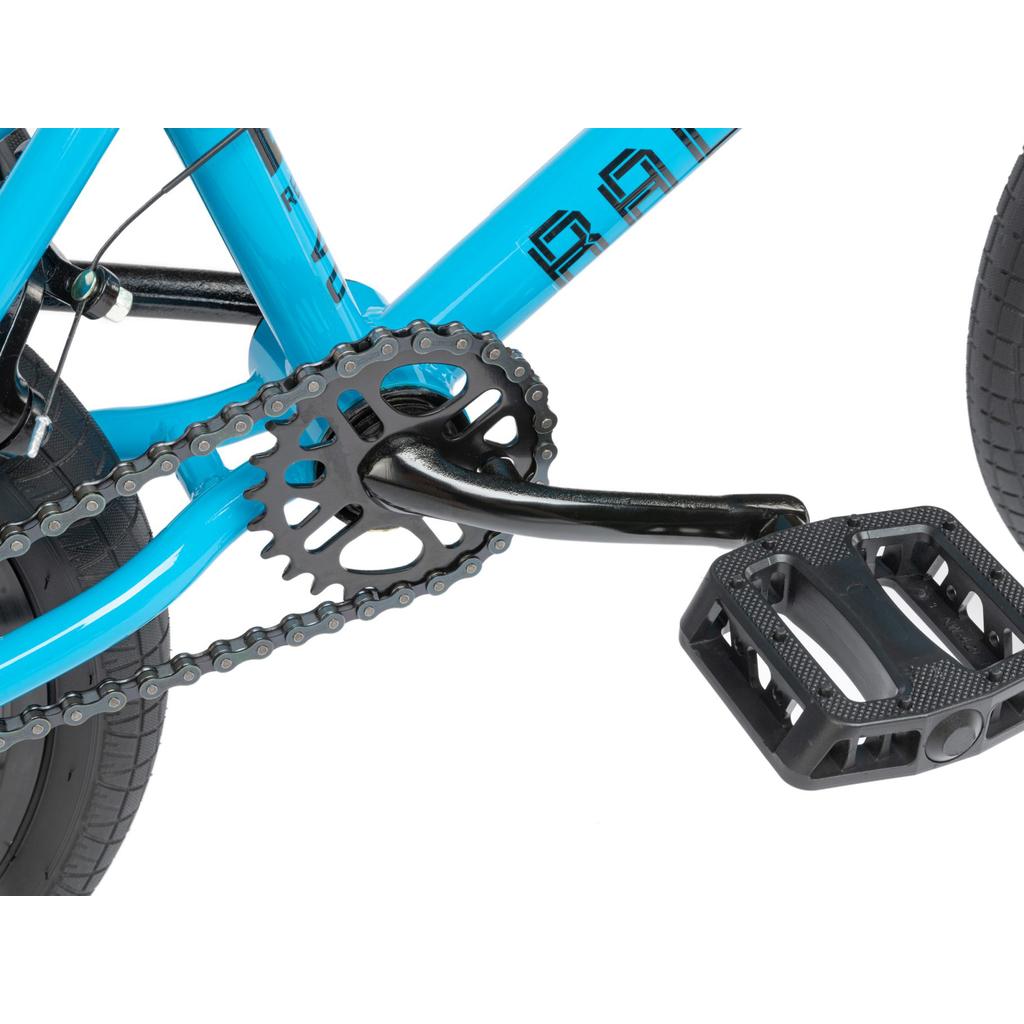 Close-up of the crankset, chainring, chain, and black pedal of the Radio Revo 16 Inch Bike in blue, with part of the rear wheel visible.